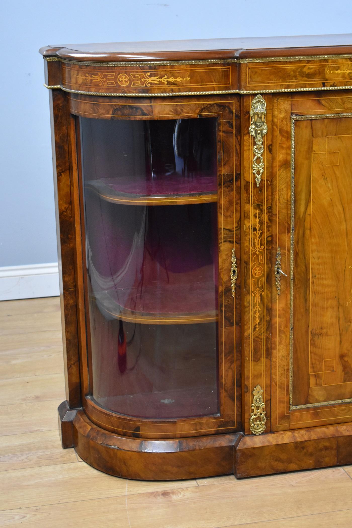 Victorian burr walnut inlaid credenza in good condition. The credenza has a decorative inlay to the centre door when opened encloses a single shelf with inlay to the sides and outer edge, it has decorative brass to the top and Ormolu mounts with a