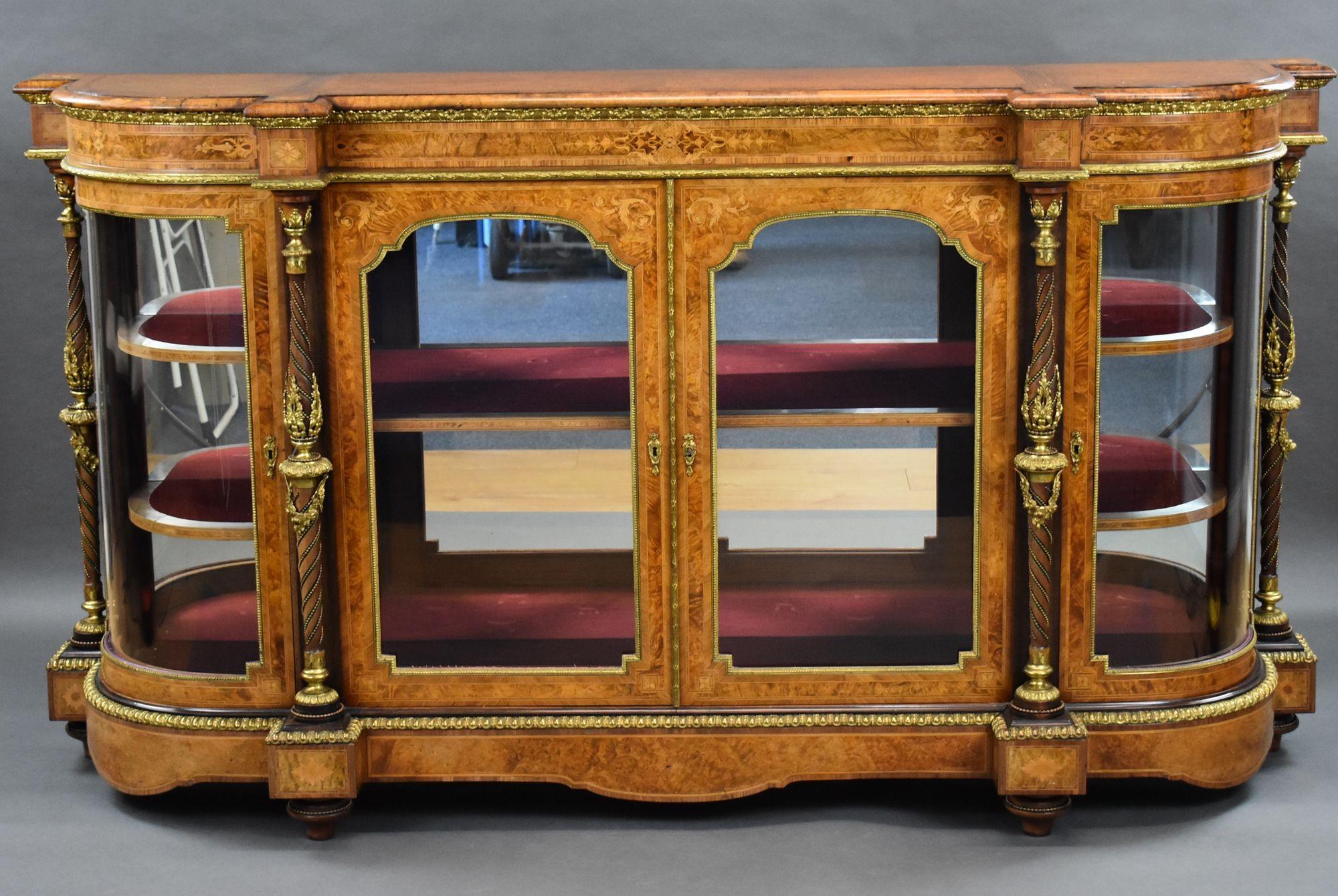 For sale is a top quality Victorian burr walnut & marquetry credenza, having an amboyna and cross banded top, above two glazed door flanked by two bowed glass doors to each end, separated by ornate columns with decorative brass work. Decorated with