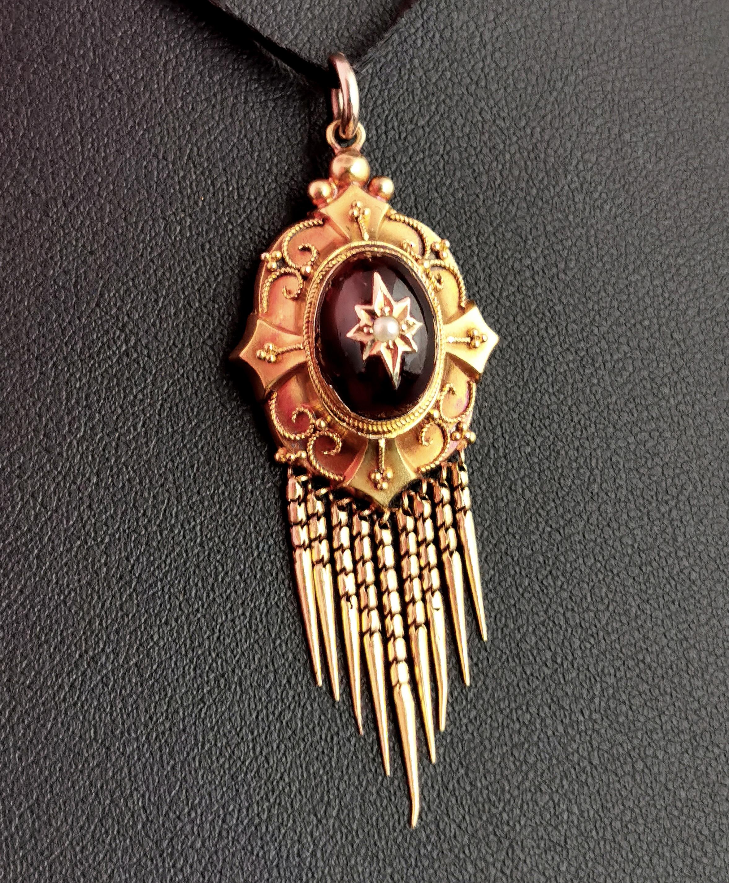 A beautiful antique, Victorian cabochon garnet and pearl tassel pendant.

The pendant is crafted from bloomed 9ct yellow gold, elaborately designed with reeded and beaded border housing a stunning rich bohemian garnet cabochon.

The pendant has a