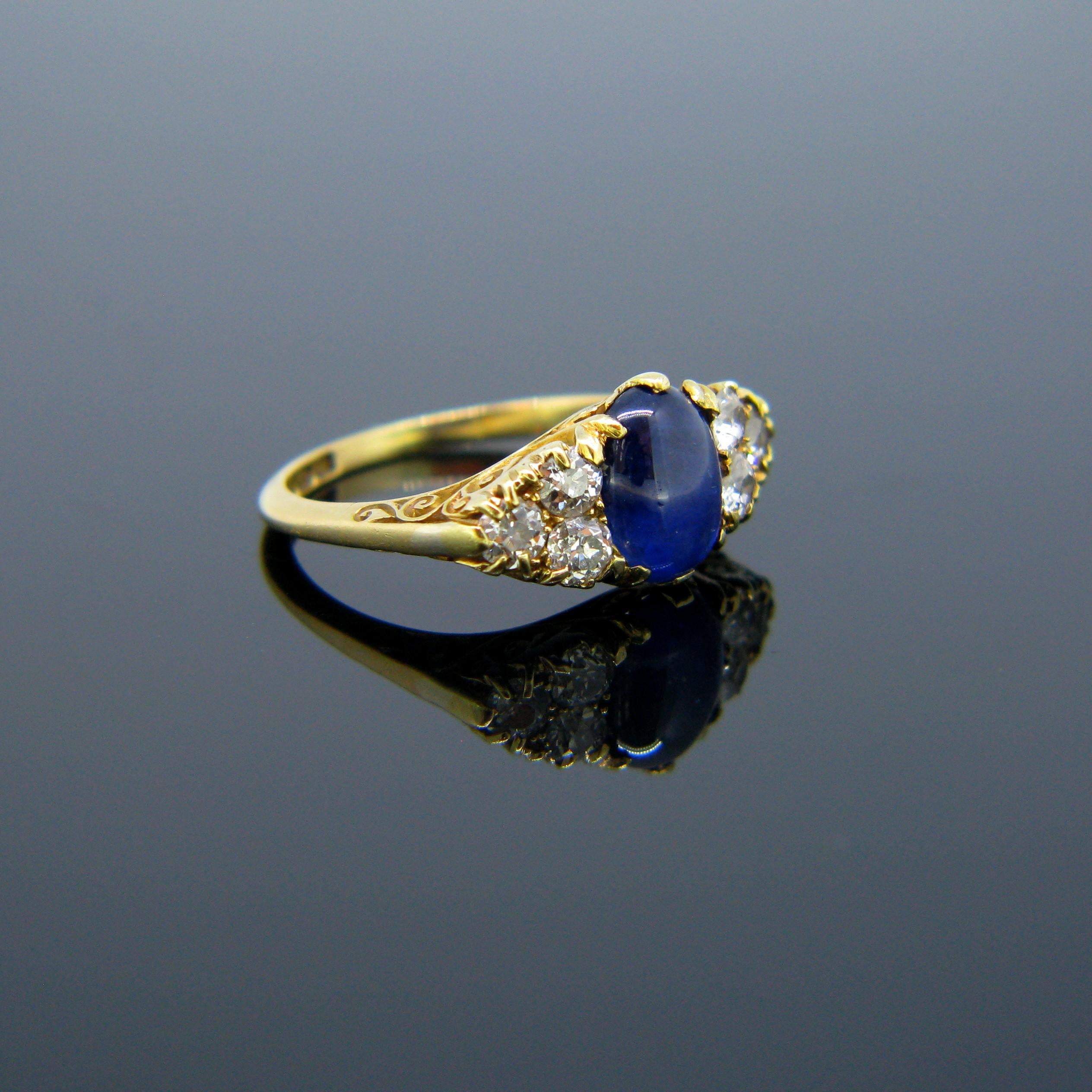 This ring is from the Victorian era. It features a cabochon cut sapphire of around 2ct and is adorned with 6 old mine cut diamonds on its shoulders for a total carat weight of 1ct approximately. The band is made in 18kt yellow gold and is marked