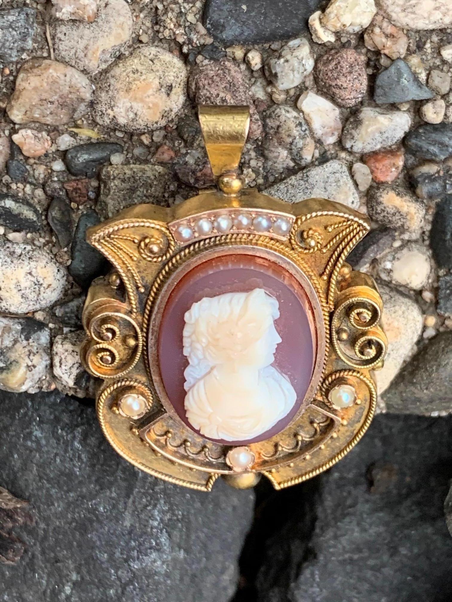 This antique Victorian stone Cameo is that of a beautifully carved lady. It is set in 14 karat yellow gold.  It can be worn as a brooch, or as a pendant with the bale on the backside of the pendant.

There is no stamp on this piece.

It features:
3