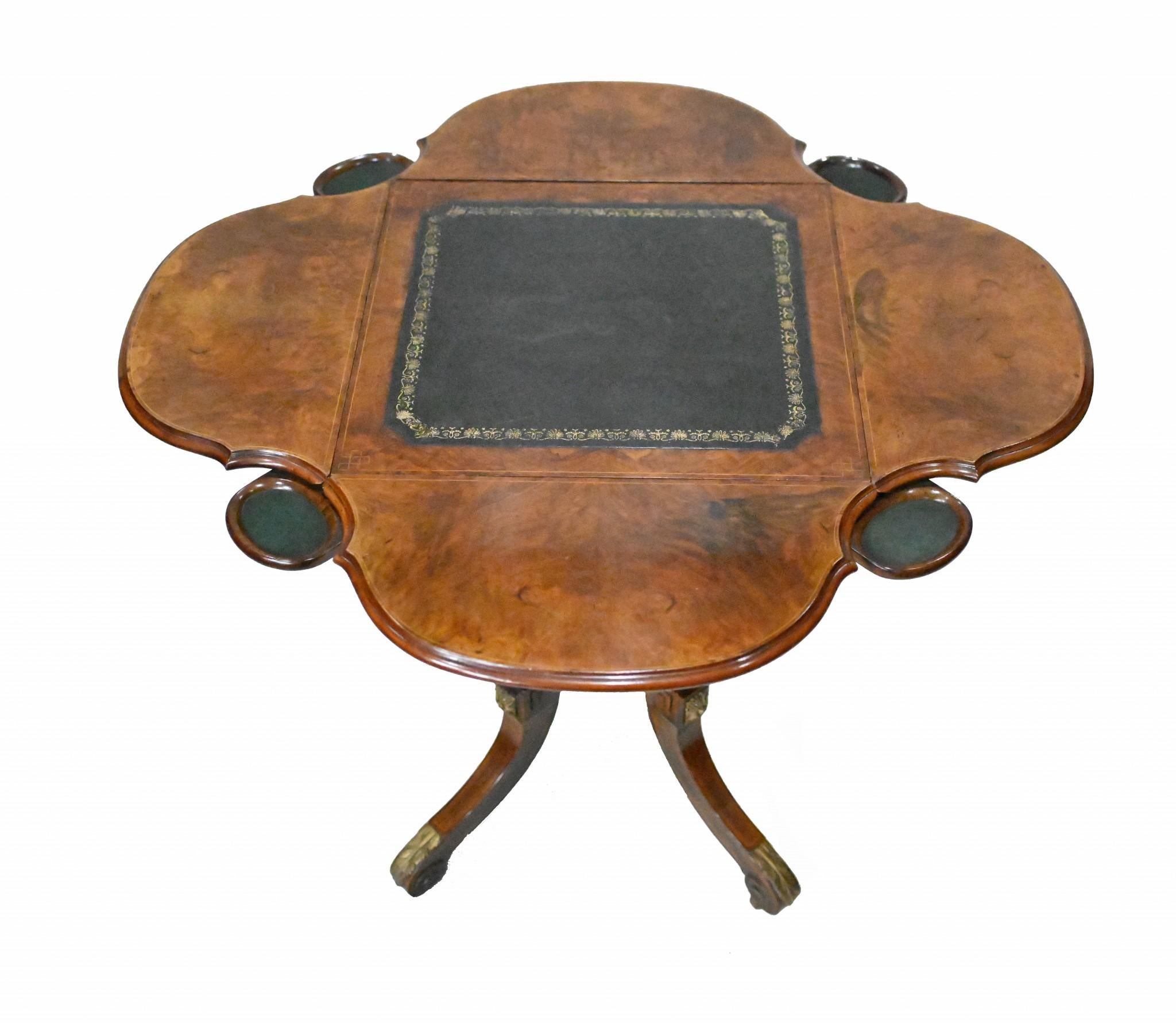 You are viewing a gorgeous Victorian bridge or games table
Hand crafted from walnut we date this piece of antique furniture to 1860
Features an unusual clover shape when fully open alongside four round trays for chips, pieces and money
Features gilt