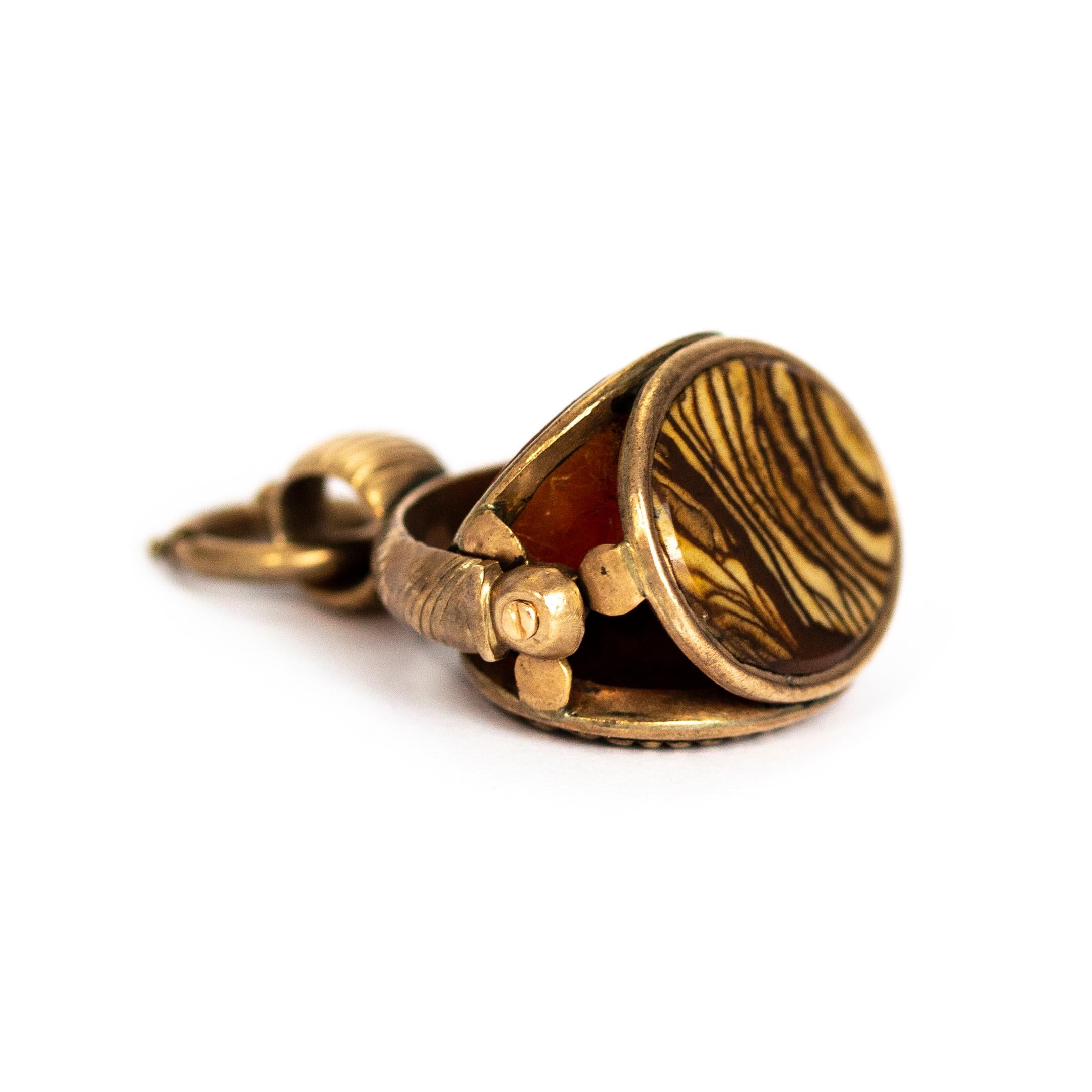 An elaborate Victorian fob pendant. Containing three oval sides of textured gold, striped agate, and carnelian forming a triple side swivelling fob. Which is pivoted beneath an textured arch and pendant loop. Modelled in 9 karat yellow