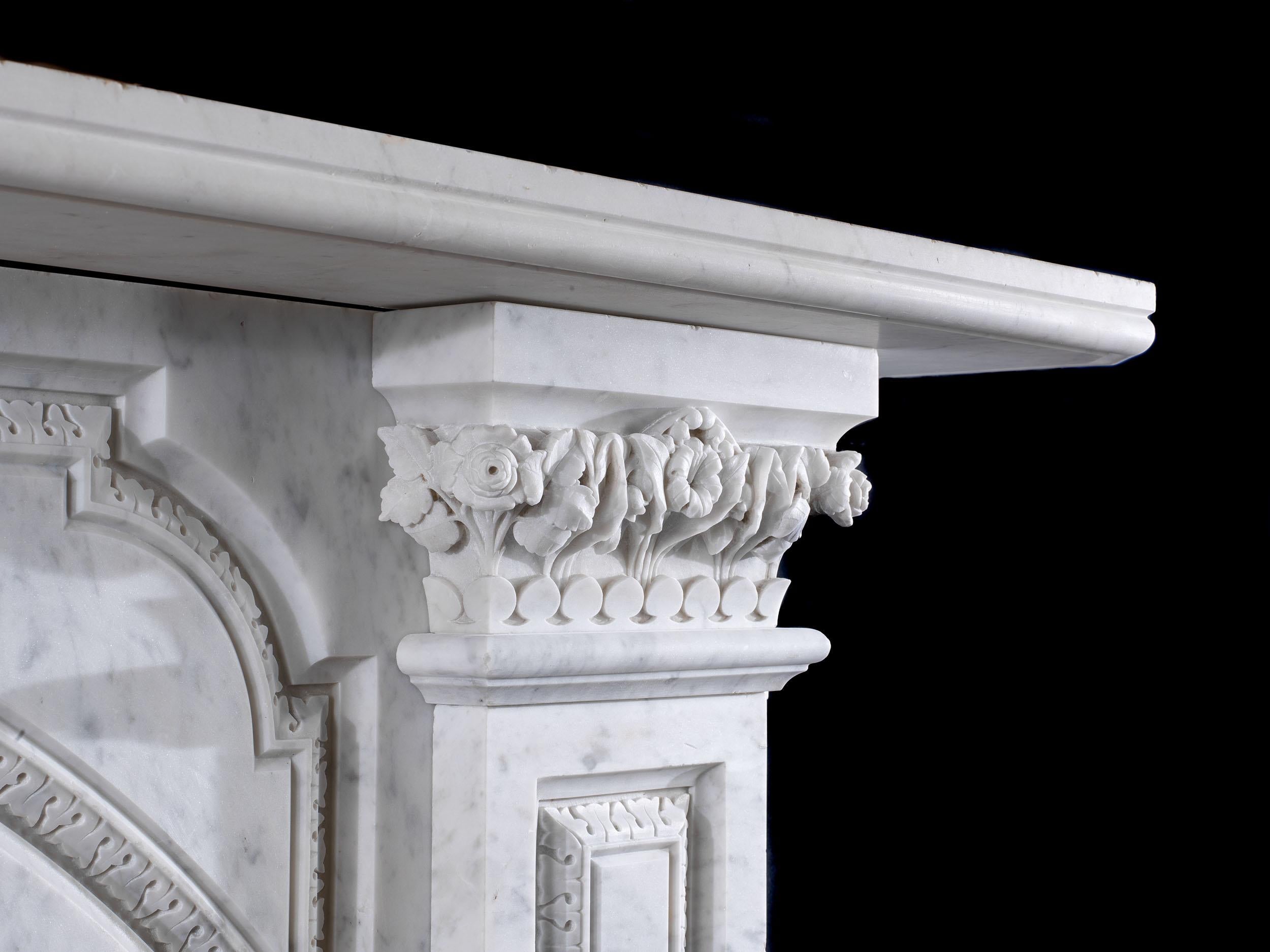 A very fine Victorian arched fireplace, carved from a delicately veined Carrara marble. The moulded shelf rests above two magnificent capitals, finely carved with lily of the valley, ferns and roses, each capital subtly different. These frame the