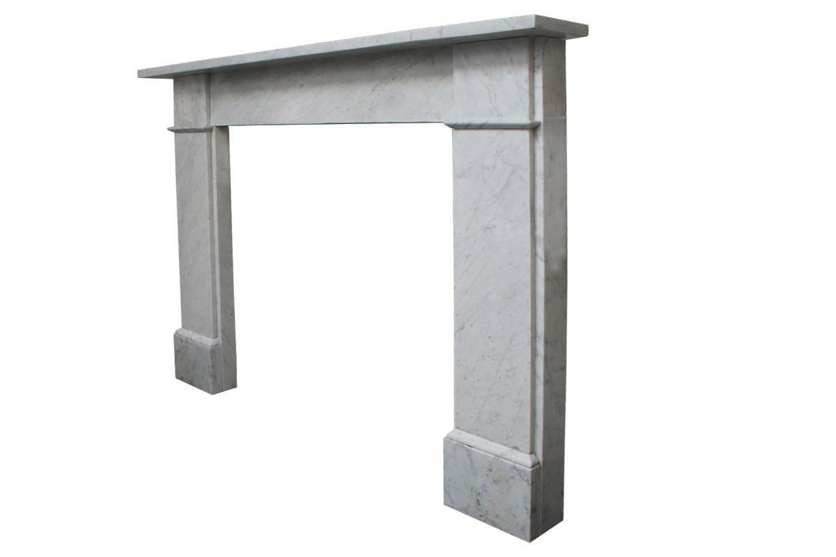 Antique Victorian Carrara marble fireplace surround of simple construction with unadorned square capitals above plain jambs, circa 1880.
We currently have a near pair of these surrounds available. 

Pictured with an original Victorian cast iron