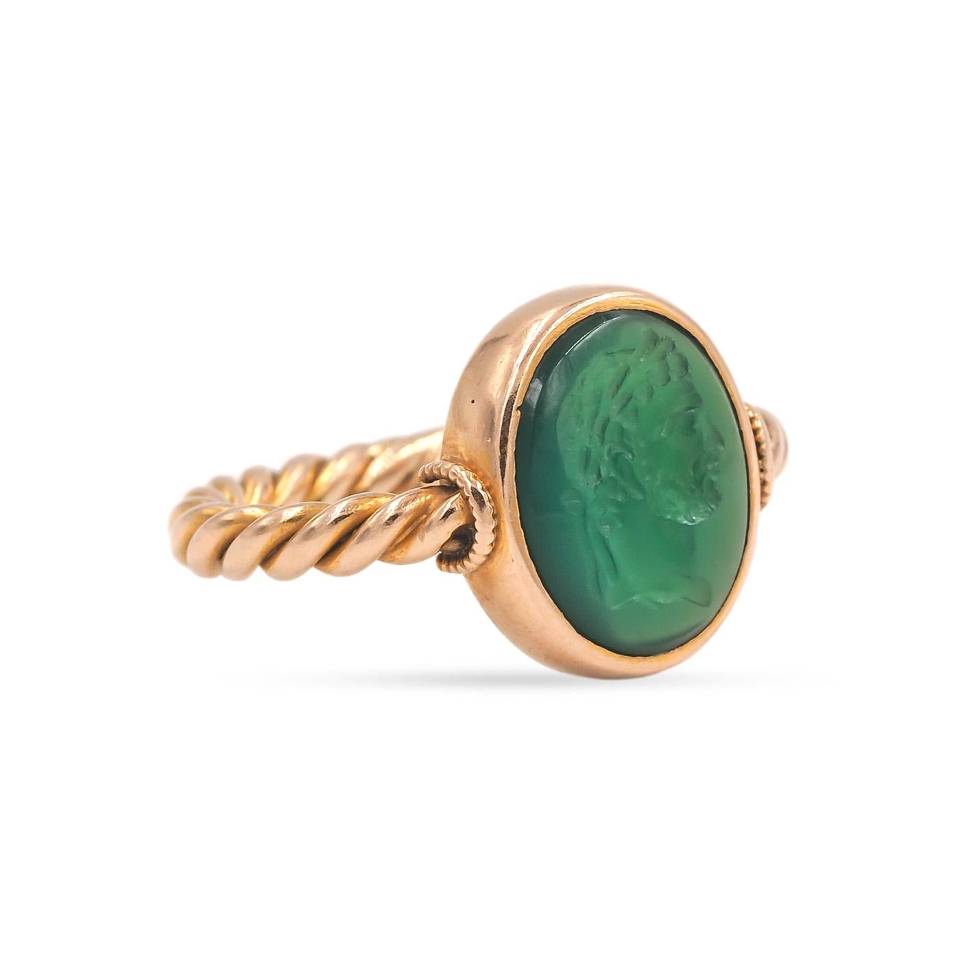 Late Victorian era Carved Chalcedony Intaglio Gold Ring composed of 18k yellow gold. With a bezel-set oval natural green Chrysoprase Chalcedony cabochon that has been carved to depict a man's profile. With a twisted rope gold shank. Center bezeled