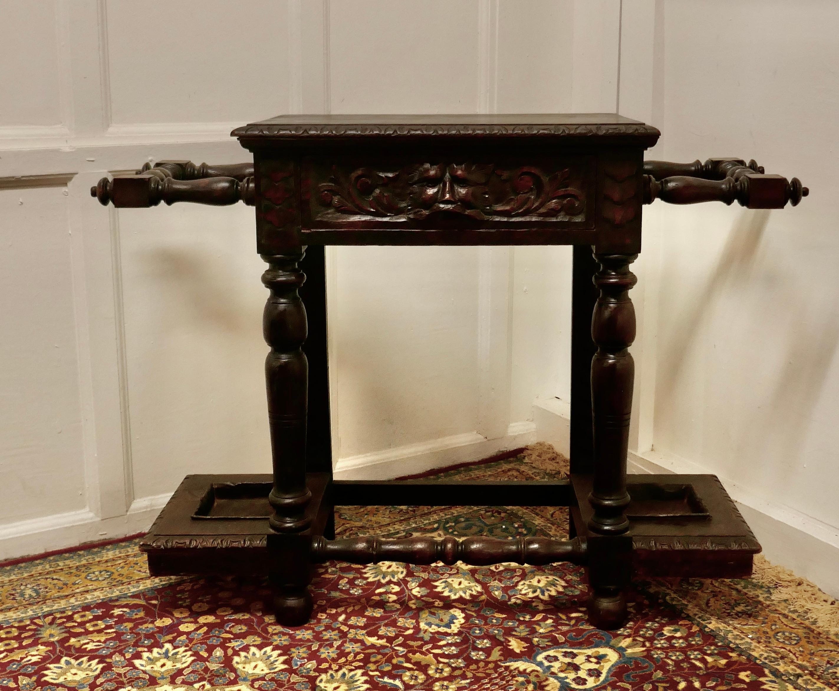 Victorian carved Gothic oak hall table, stick stand 

This attractive hall table is made in oak, the drawer front has a magnificent green man handle carved on it and at at each end there is a turned oak umbrella stand with metal drip tays at the
