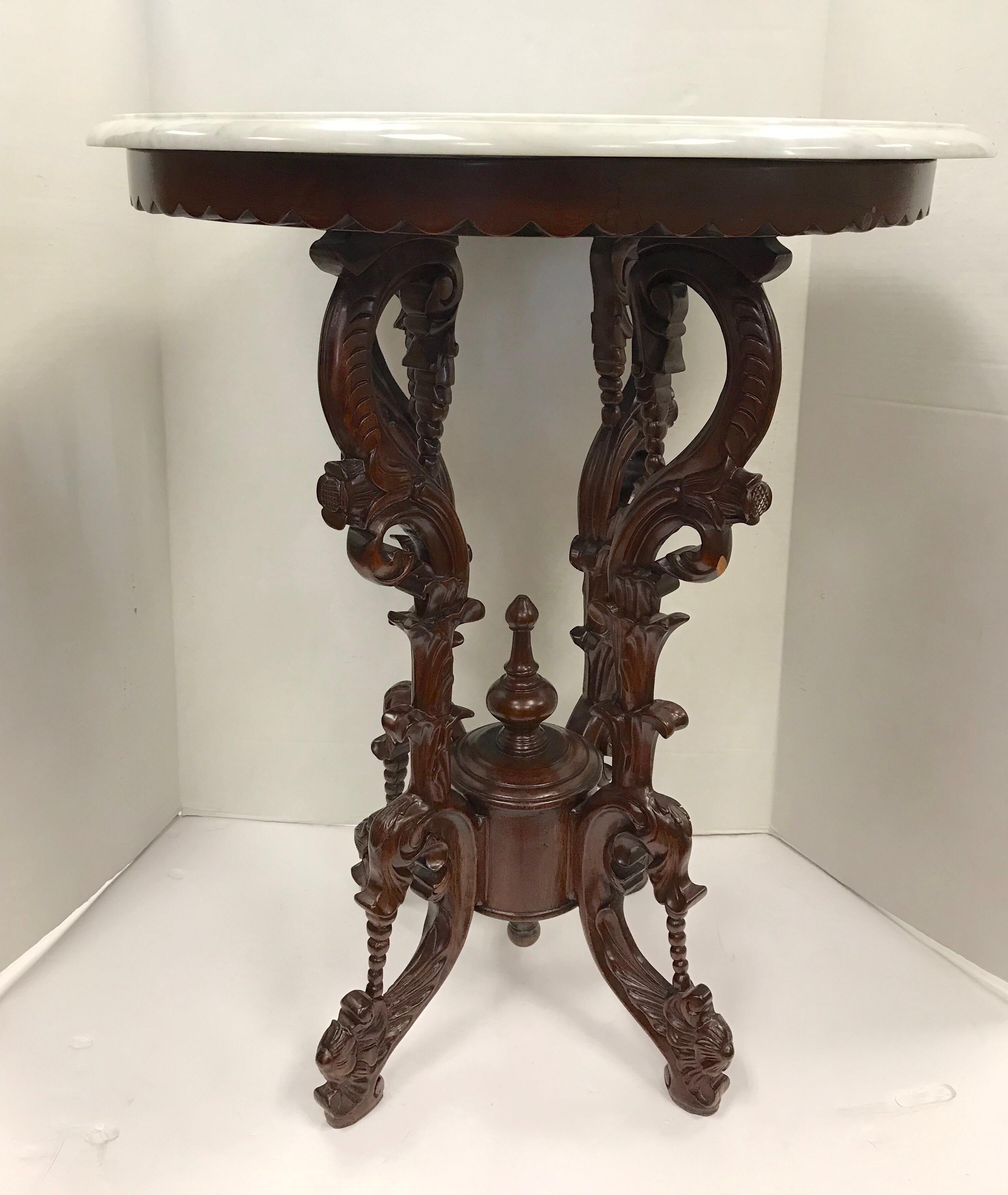 Elegant intricately carved mahogany round table with marble top.