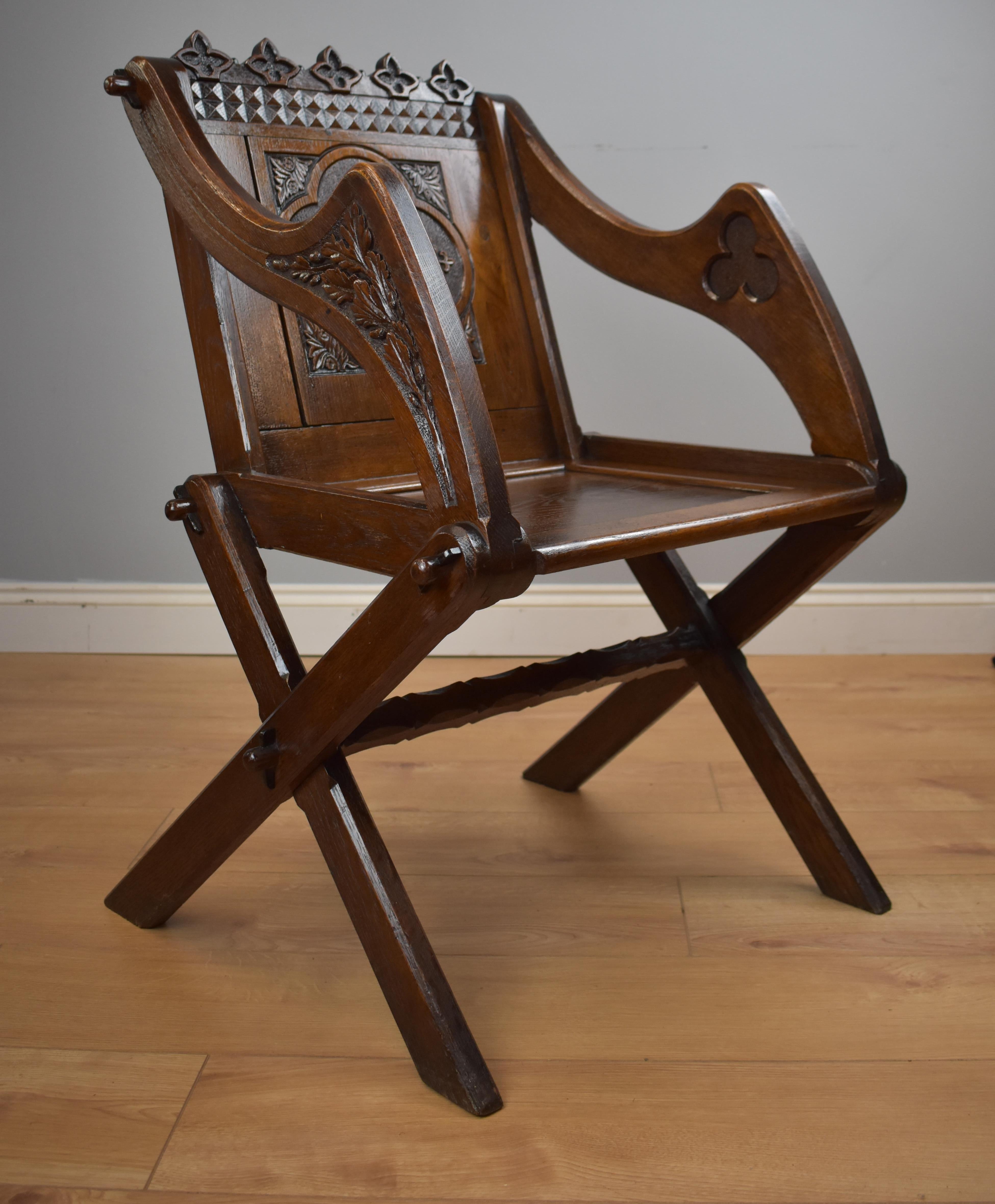 Victorian carved oak Glastonbury chair with a nicely carved panelled back and seat with its carved to the back a monogram symbolising Jesus Christ, the chair is in good condition on chamfered x-frame supports, carved to underside of seat 