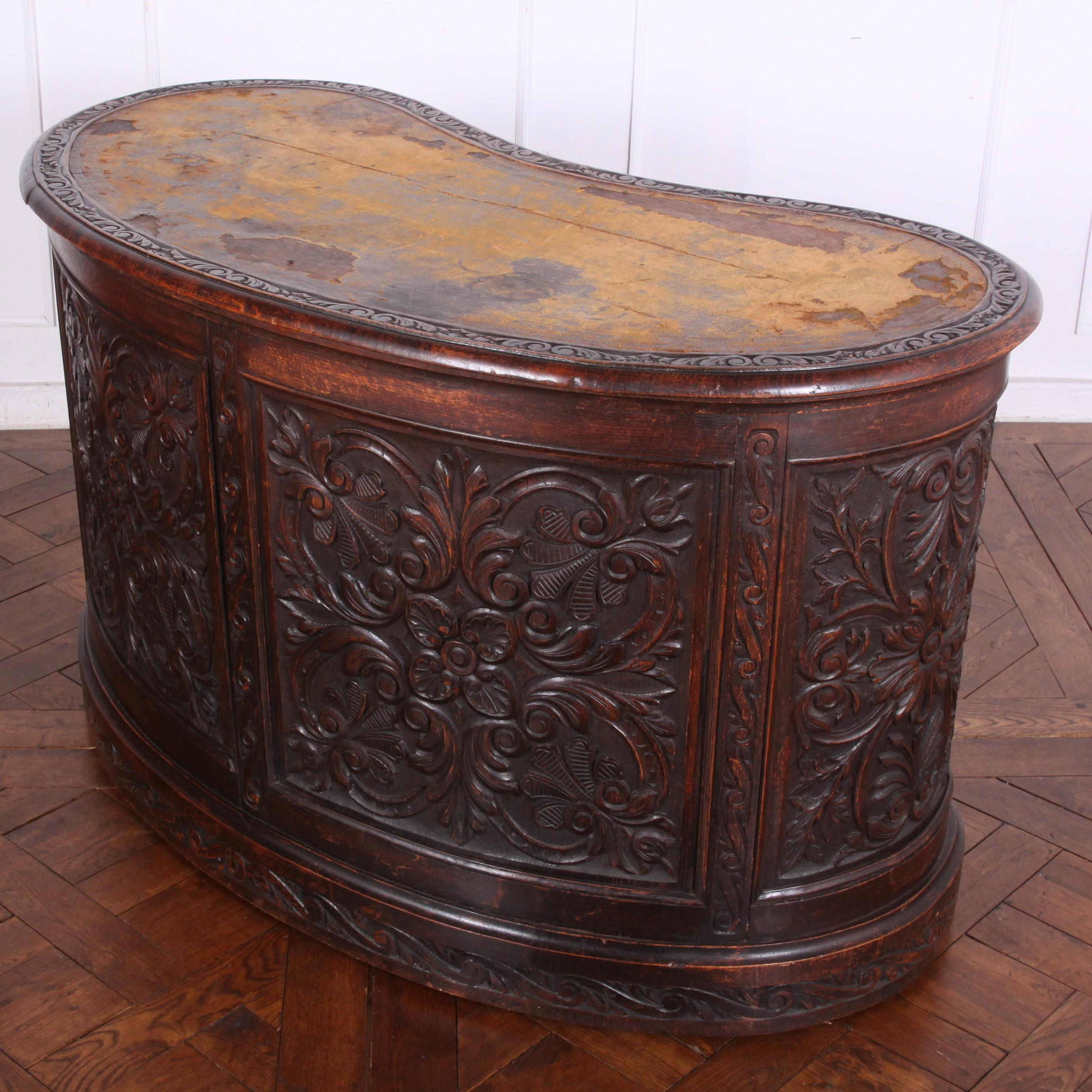 Rare English Victorian oak kidney-shaped desk, the curved panelling profusely carved in a Renaissance-revival style. Eight carved-front drawers flanking a single upper central drawer. Original leather showing considerable wear; new leather top will