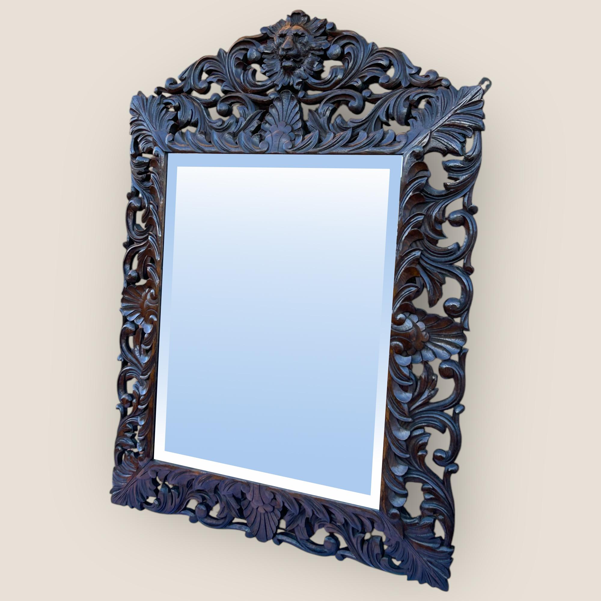 A Victorian Carved Oak Mantel Mirror with intricate carvings throughout and a centrepiece carved lion to the top. The mirror glass is bevelled and the frame has to wall hangers to the back, one each side. There is a slight mark to the mirror which