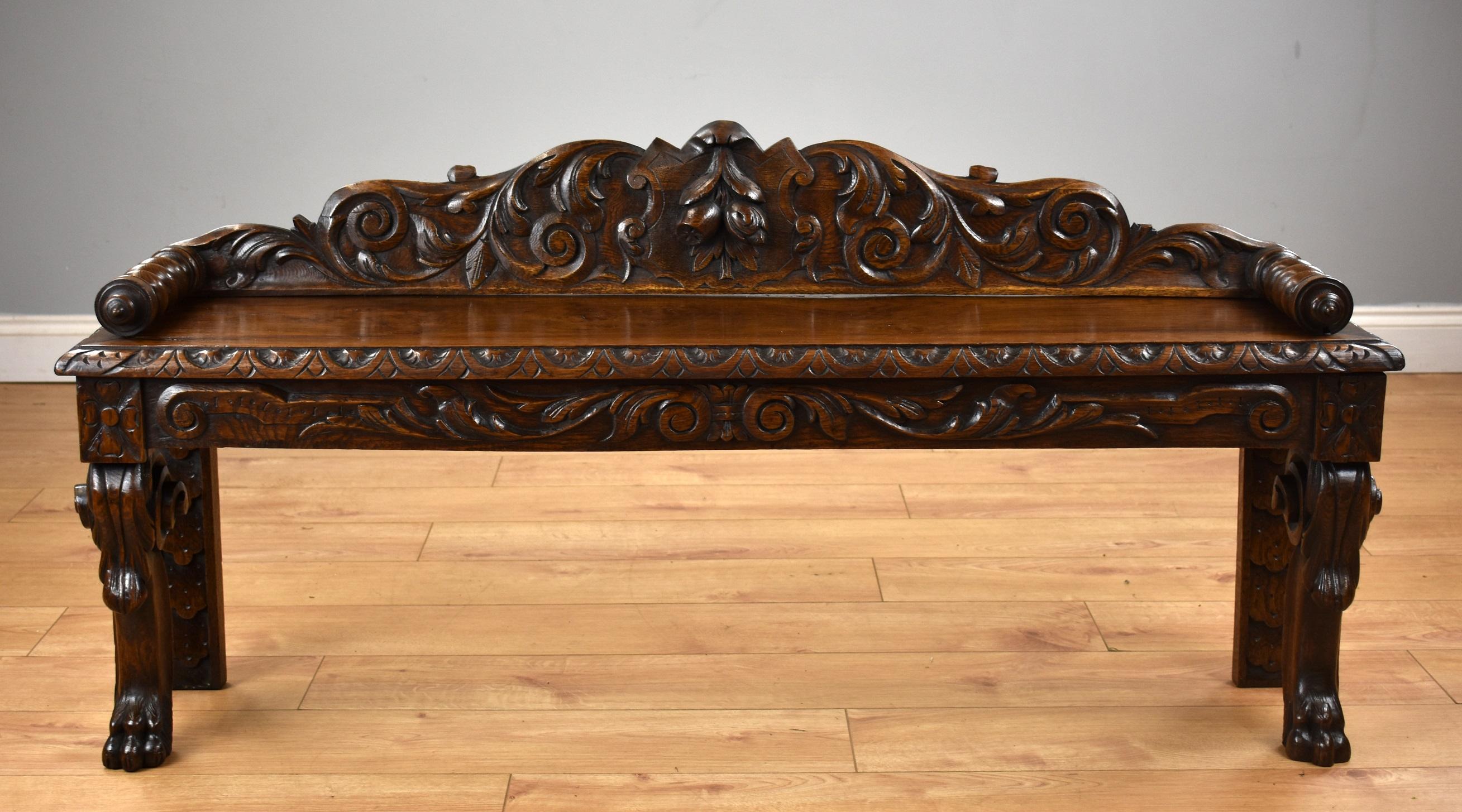 Victorian carved oak window seat in good condition having been recently polished by hand. The seat has a profusely carved back with turned arms, with a detailed scrolled edge to the seat standing on carved legs graduating to claw feet.