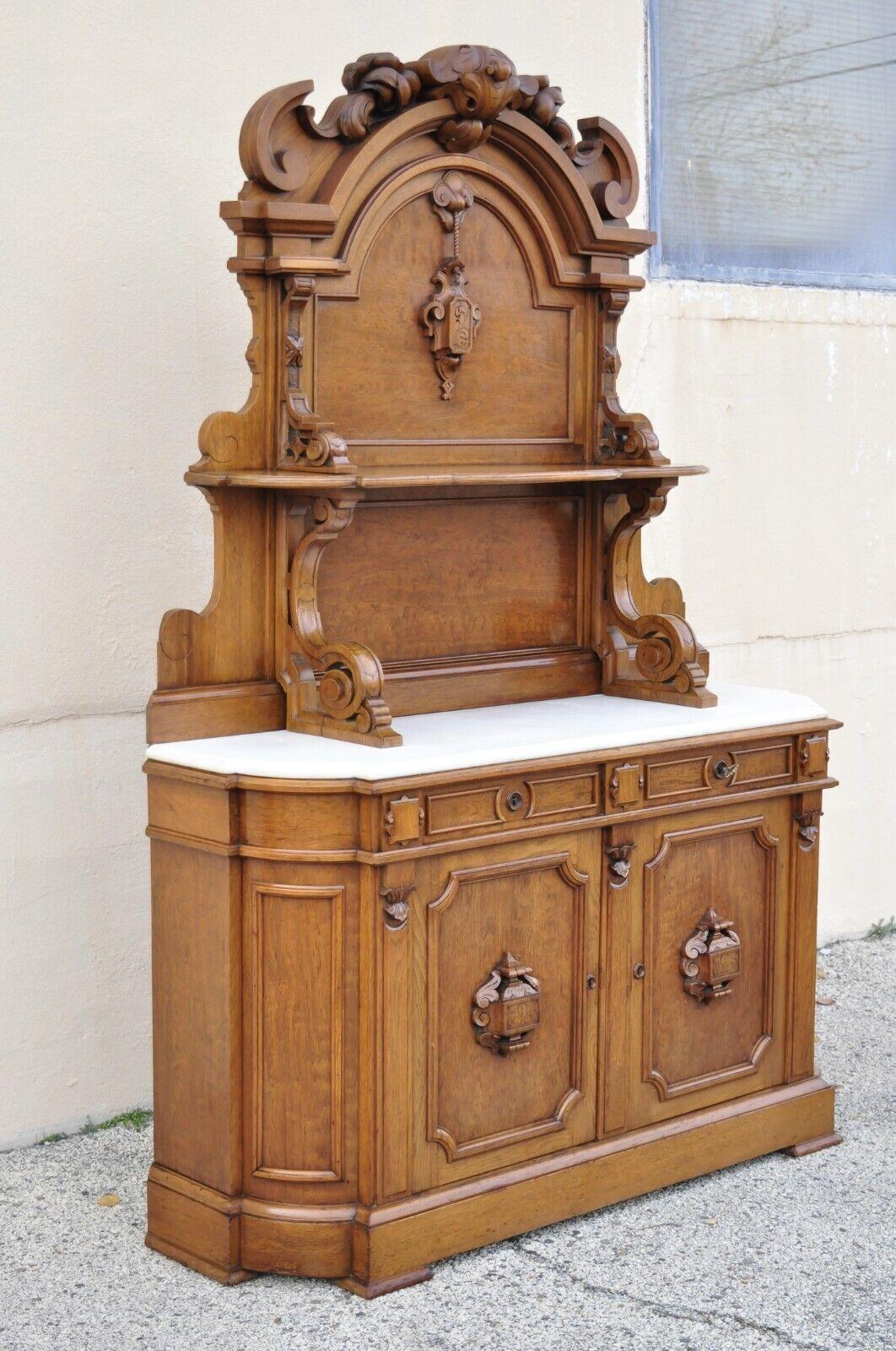 Antique Victorian Carved Walnut Marble Top Custom Sideboard Buffet Cabinet with Backsplash. Item features a tall impressive backsplash with upper shelf and ornate carvings, white marble shaped top, solid wood construction, beautiful wood grain, 3