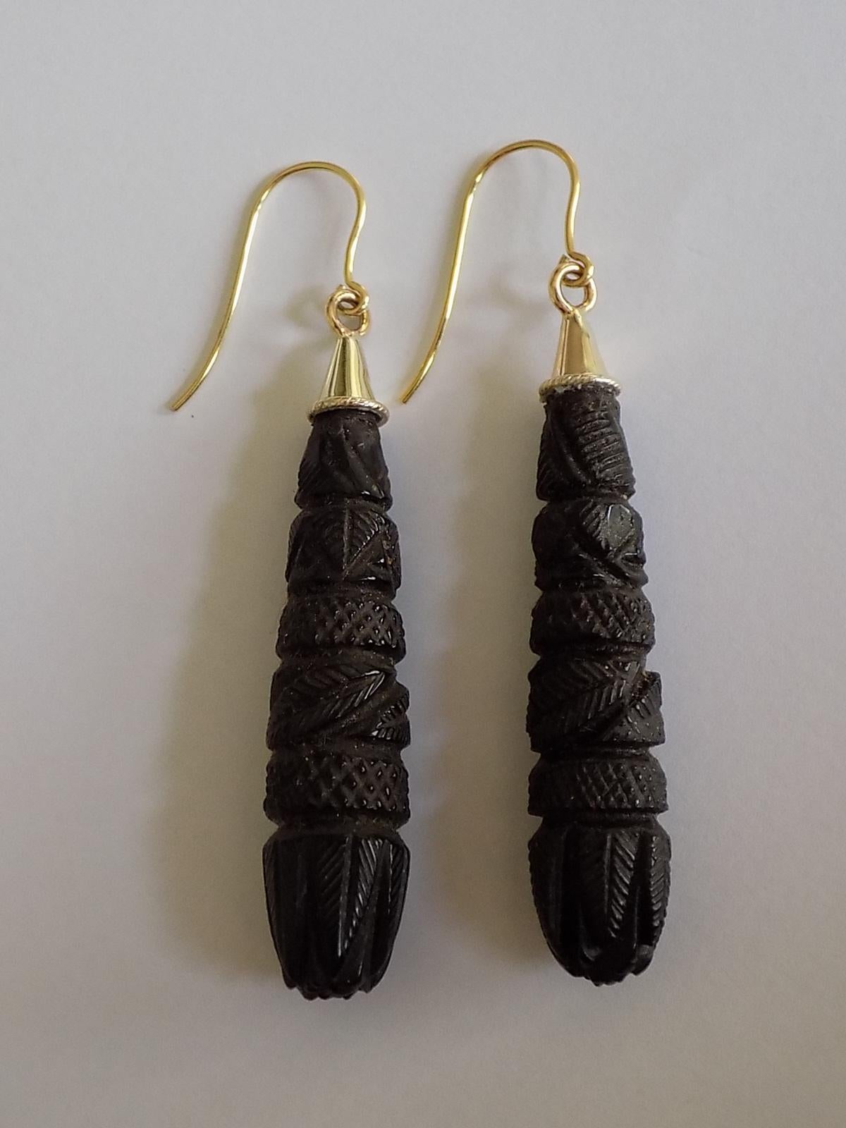 A Classic Victorian c.1880 carved Whitby Jet drop earrings for pierced ears. The earrings complete with a brand new 9 Carat Gold hook wires. English origin. 
Total drop including hooks 60mm
Width of the drop 10mm.
Weight 5.8gr.
Hooks marked 375 for