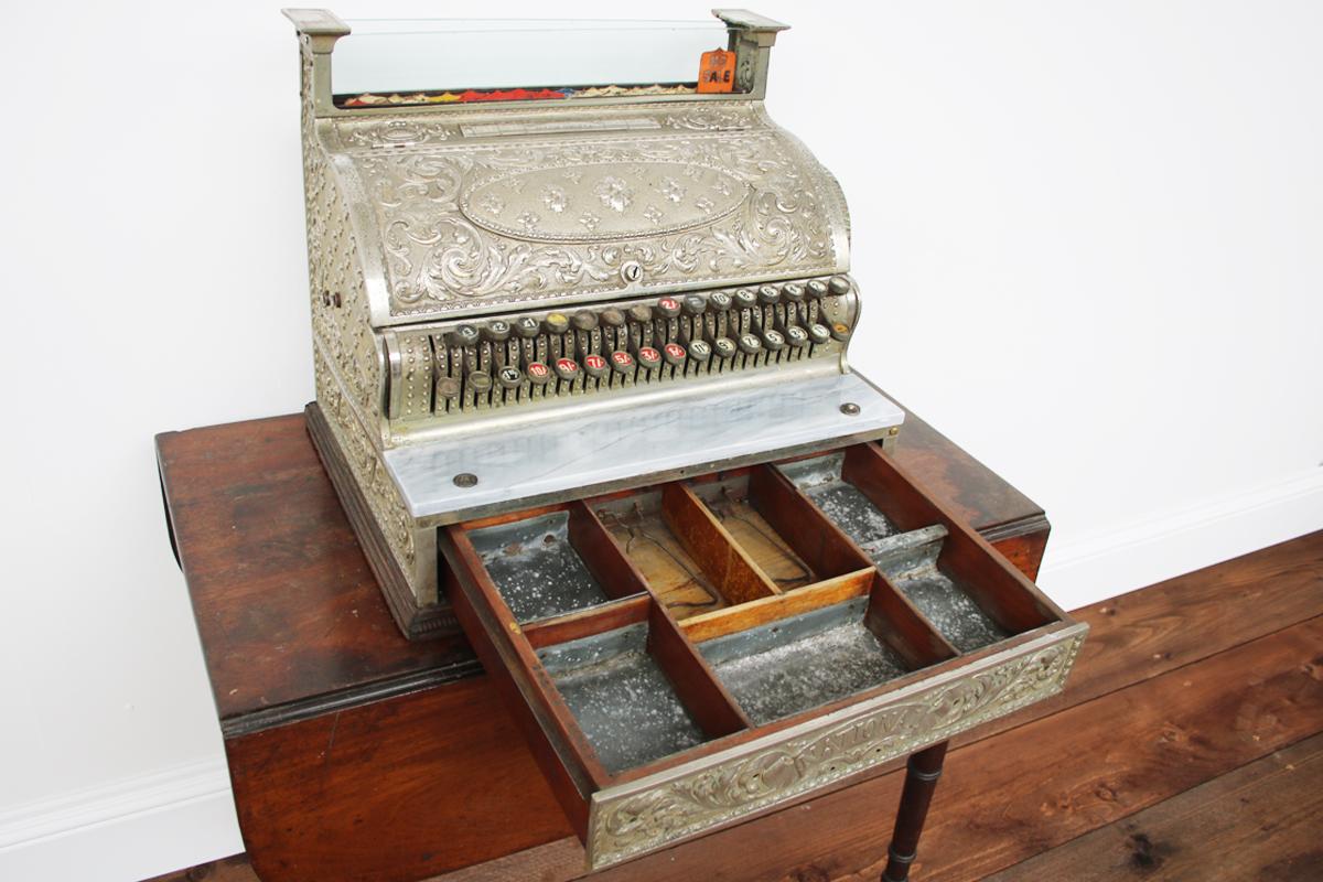 Victorian cash register by National Cash Register Co., Ohio, USA. Made of solid brass & then coated in Nickel, which made it very heavy (approximately 50kg) & harder to steal. The grey marble ledge on the front was used to tap coins to rule out