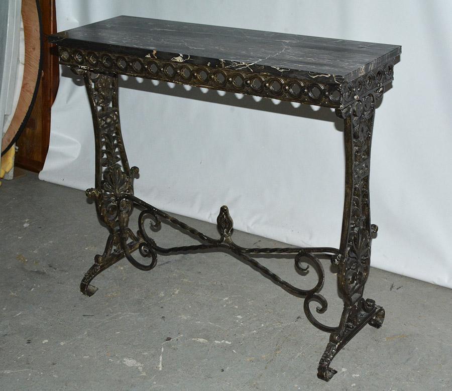 The base of the Victorian console table with marble top is made of cast iron featuring acanthus leaves and wrought iron stretchers. The apron is embellished with a classical guilloche pattern. The piece is painted black touched with a light gilt