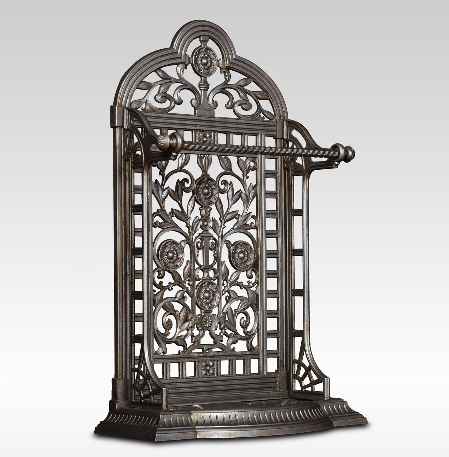 Porte-parapluie / bâton en fonte de style Coalbrookdale, de l'époque victorienne, avec sommet arqué et dos percé avec tête de fleur et rinceaux feuillagés. La base comporte un égouttoir amovible en forme de coquille, le tout reposant sur un