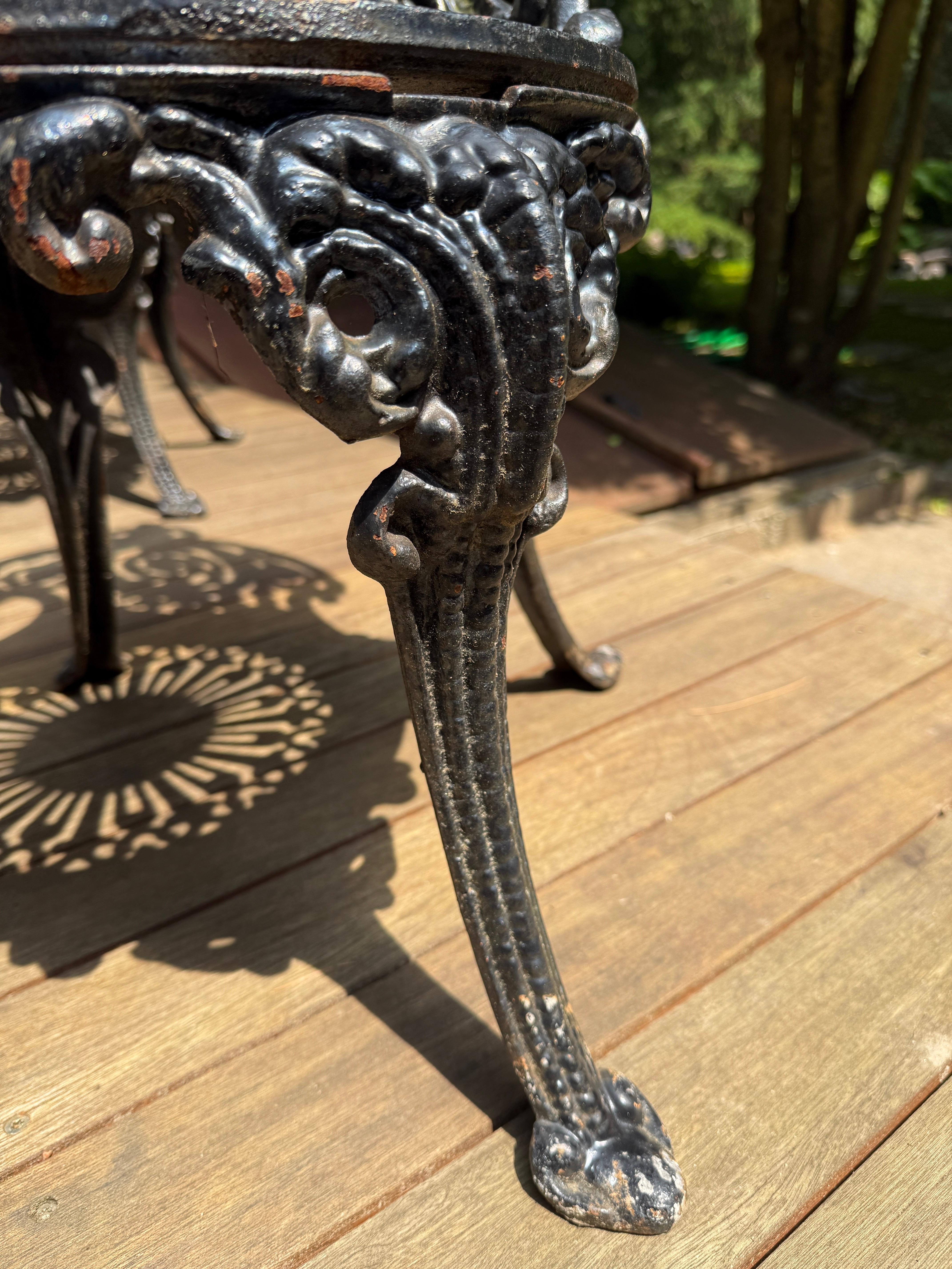 This heavy antique Victorian garden set, comprised of 3 chairs and a table, decorated with Victorian flourishes throughout.  The table top is removable for easy moving.  In original black cast iron finish with normal signs of patina, oxidation and