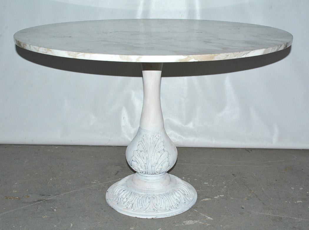 The Victorian cast iron table base painted white has a secured square masonite board, on which sits a veined white marble round top. The base is adorned with acanthus leaves. Picture the table for either indoor or outdoor placement. Table is