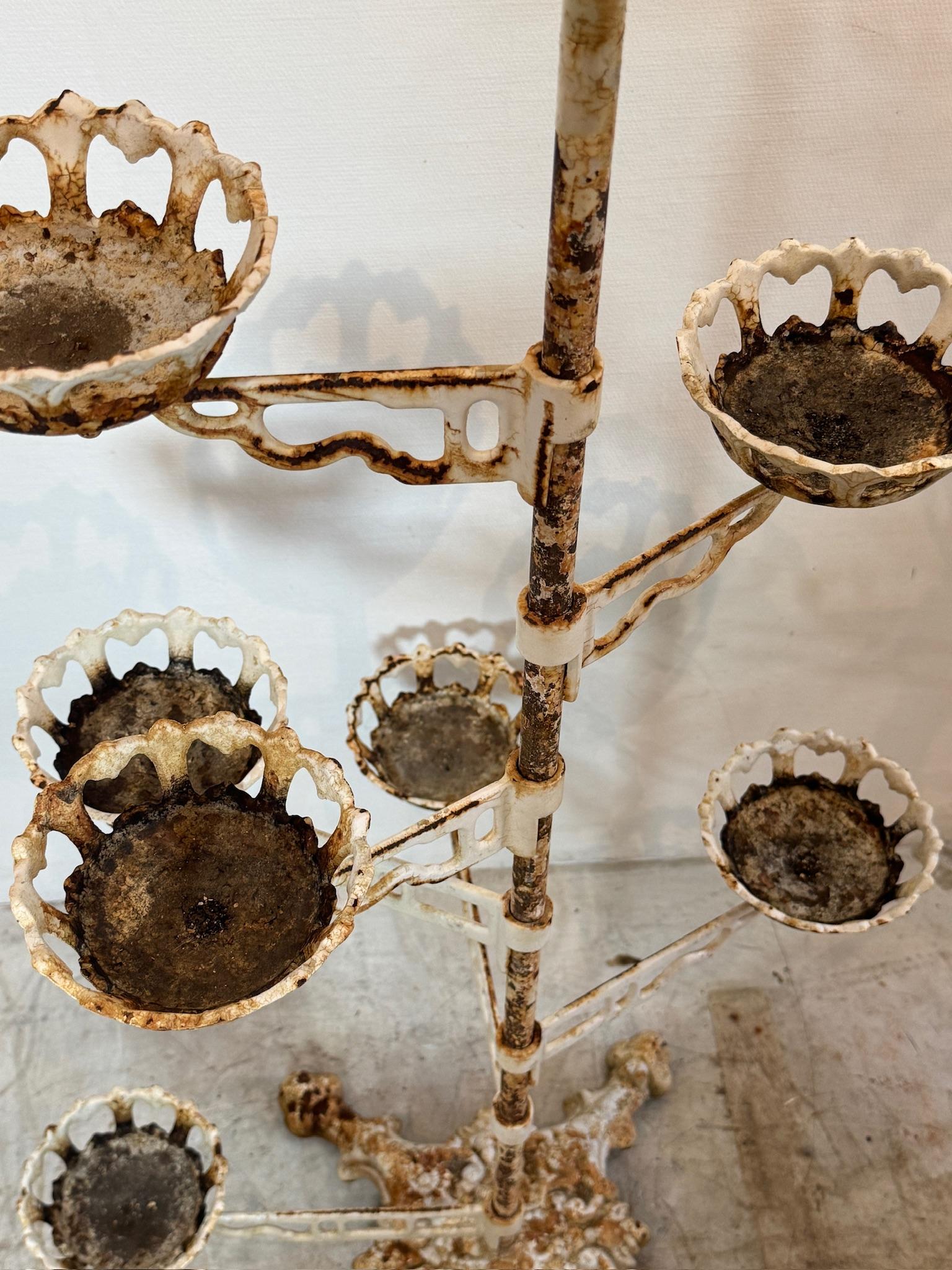 This Victorian cast iron revolving arm plant stand is a striking example of antique craftsmanship and enduring design, seamlessly blending functionality with ornate visual appeal. Featuring a central vertical post anchored by a heavily detailed