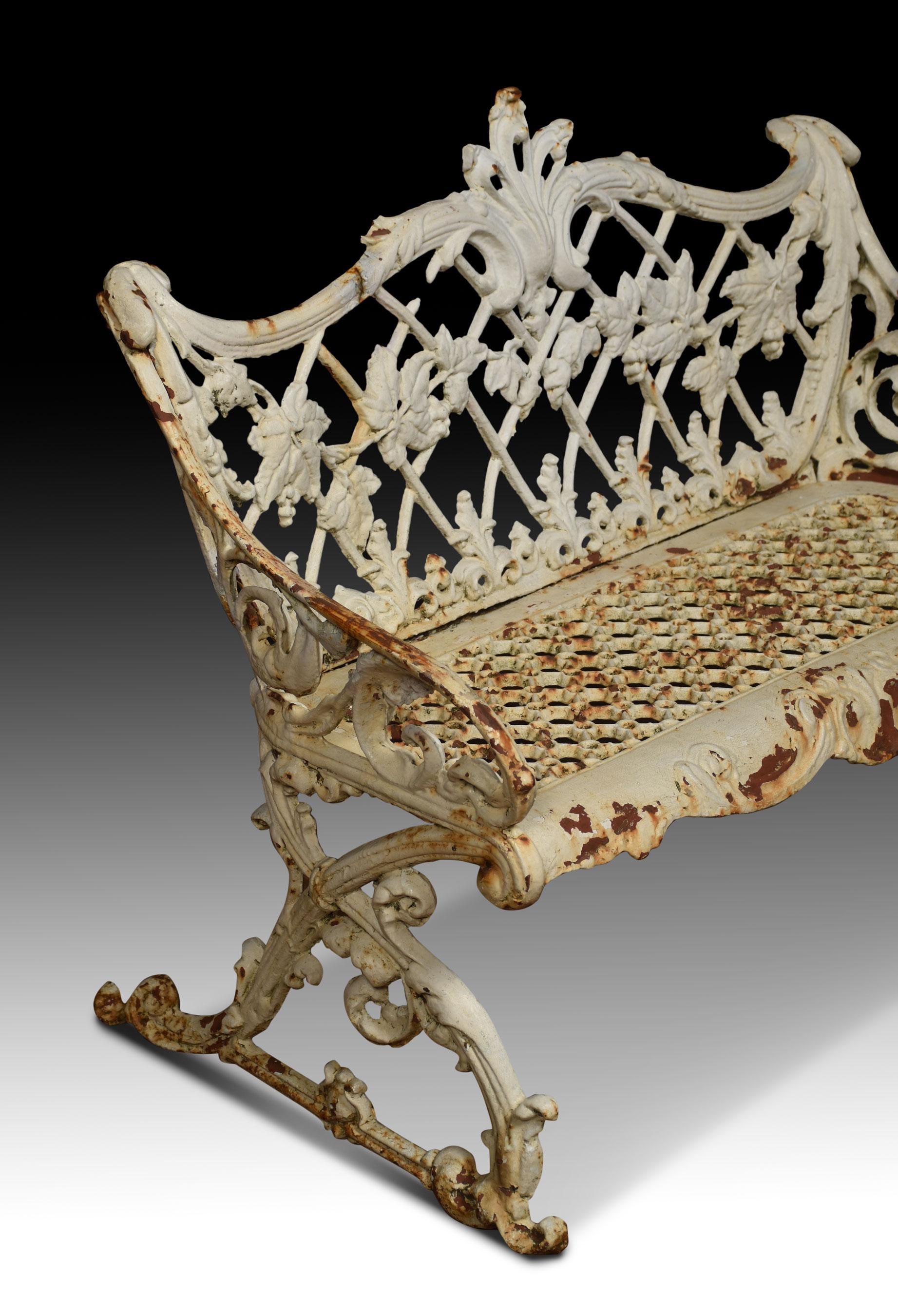 Victorian cast iron seat. The serpentine scrolling and lattice pierced backrest entwined with trailing blackberry and leaves below, the seat pierced with conjoined hexagons above the foliate apron. All raised up scrolling end