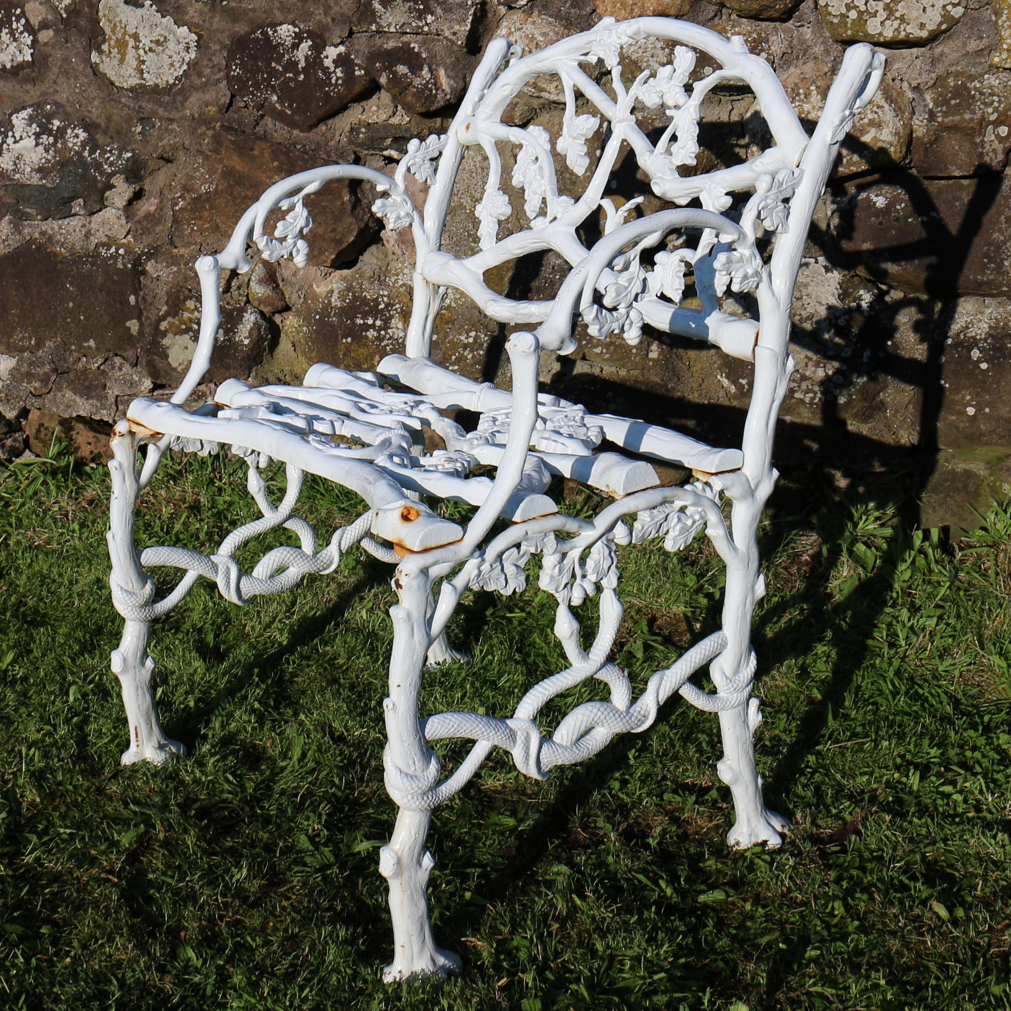 A Victorian cast iron garden seat in the serpent and twig pattern and dating to circa 1860. This beautiful rustic naturalistic casting is based on the English oak tree and depict branches adorned with oak leaves, acorns and intertwined serpents. The