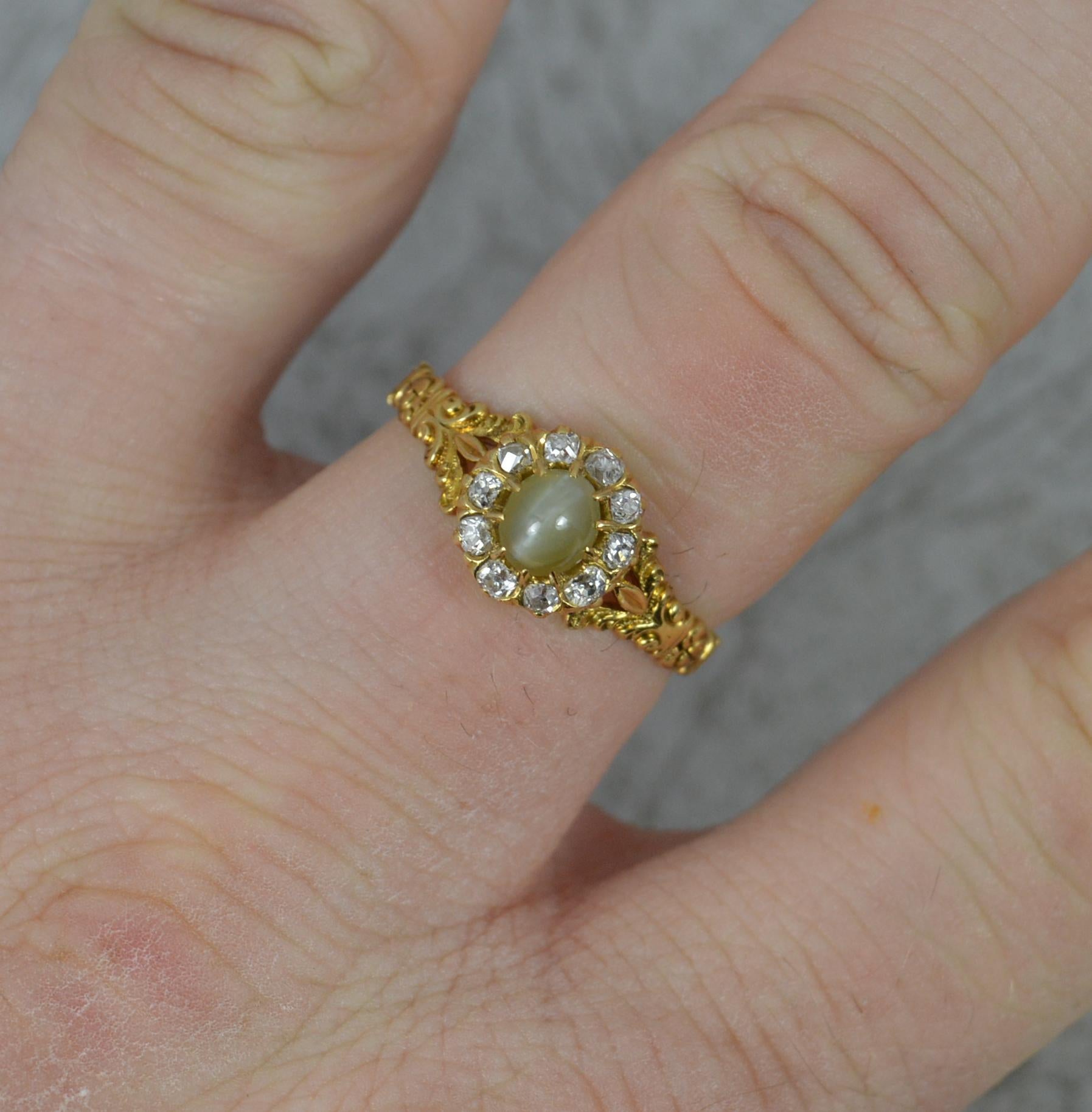 A fine antique chrysoberyl cats eye and diamond ring.
18 carat yellow gold example.
Designed with a cats eye chrysoberyl to the centre in claw setting. Surrounded by a full border of smaller old cut diamonds. Bright, white and sparkly.
8.2mm x 9.0mm