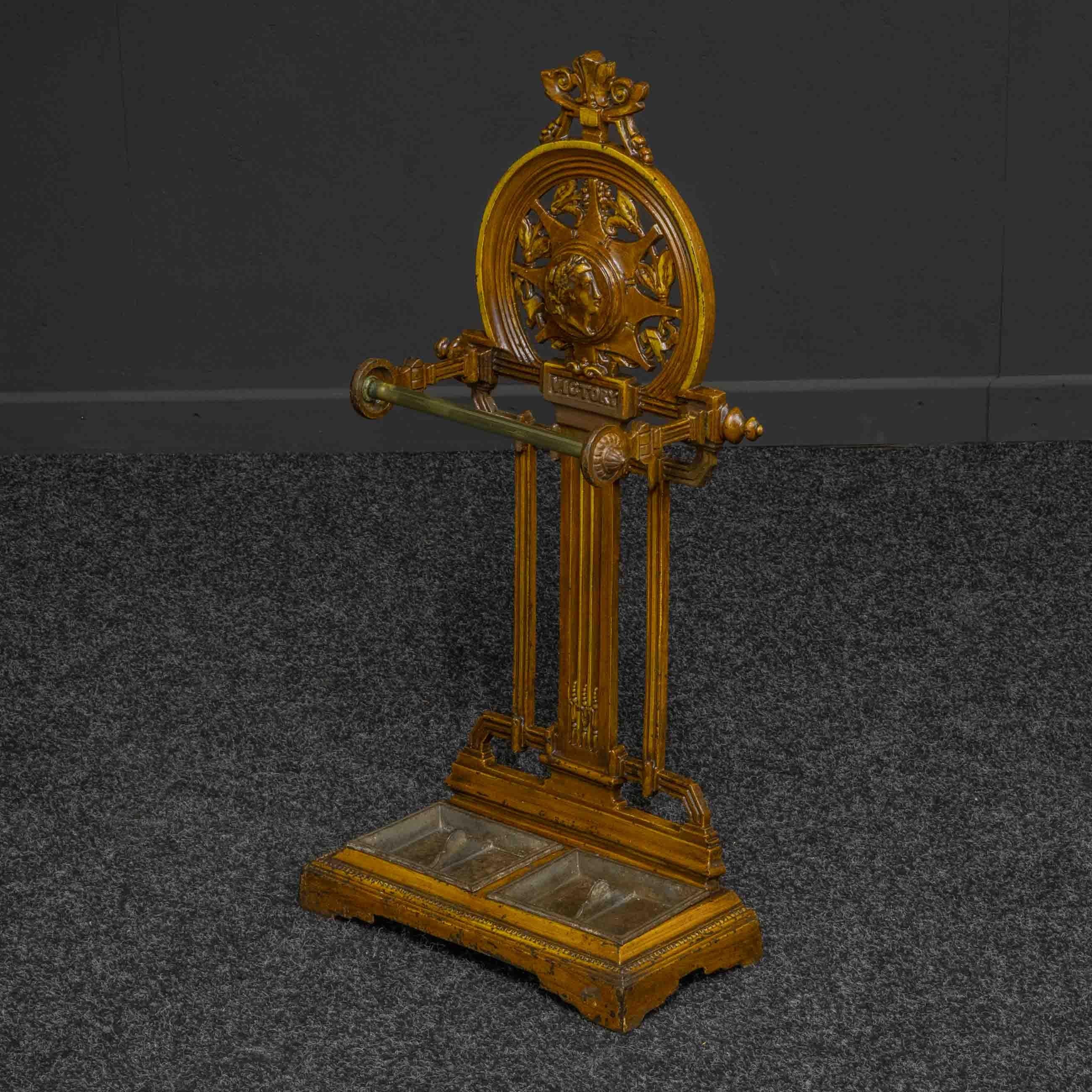 This is a rare commemorative Victorian period walking stick stand decorated with a classical head above the word 'Victory'. Very unusual to be stove enameled and with several casting numbers to the rear and the drip pans.