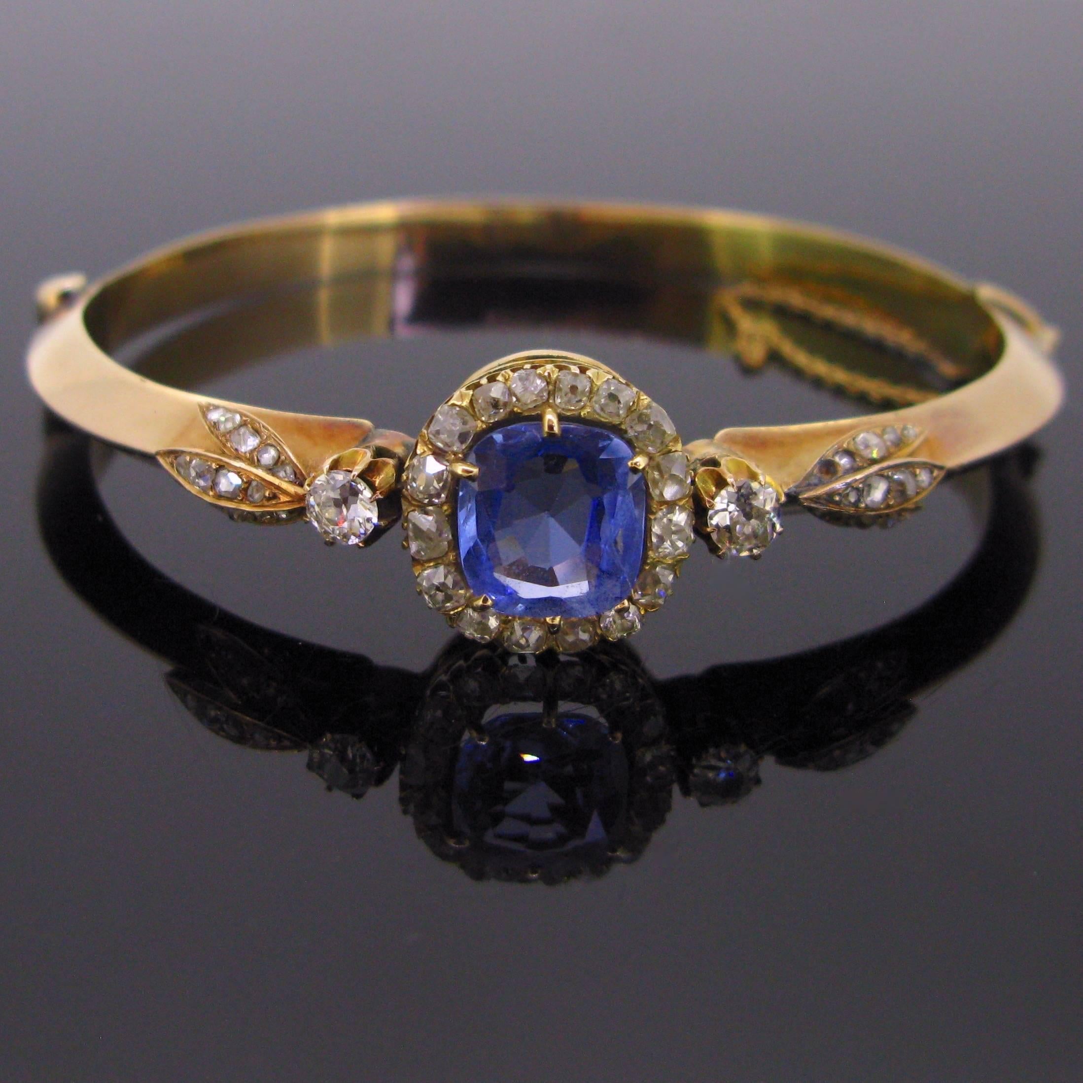 This beautiful bangle is set with a Ceylon sapphire with no indication of heating. This stunning blue sapphire is around 3.60ct. It is surrounded with 16 old mine cut diamonds. The shoulders of the ring are enhanced with an old mine cut diamonds and