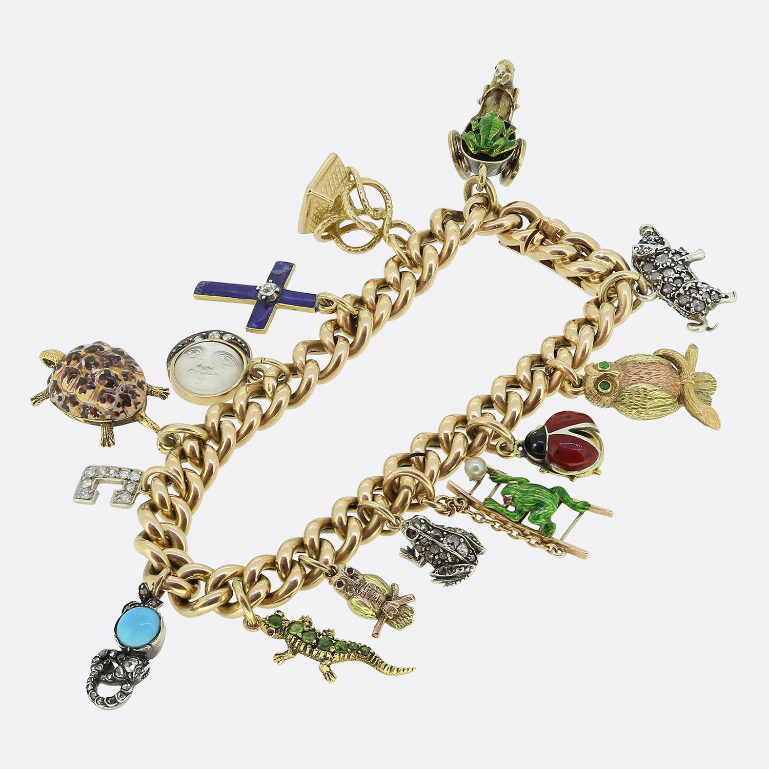 Here we have an outstanding Victorian charm bracelet crafted from 15ct yellow gold. The antique piece features an array of intricate charms, each with unique designs and materials. Among the charms, you'll find a cross adorned with blue enamel, a