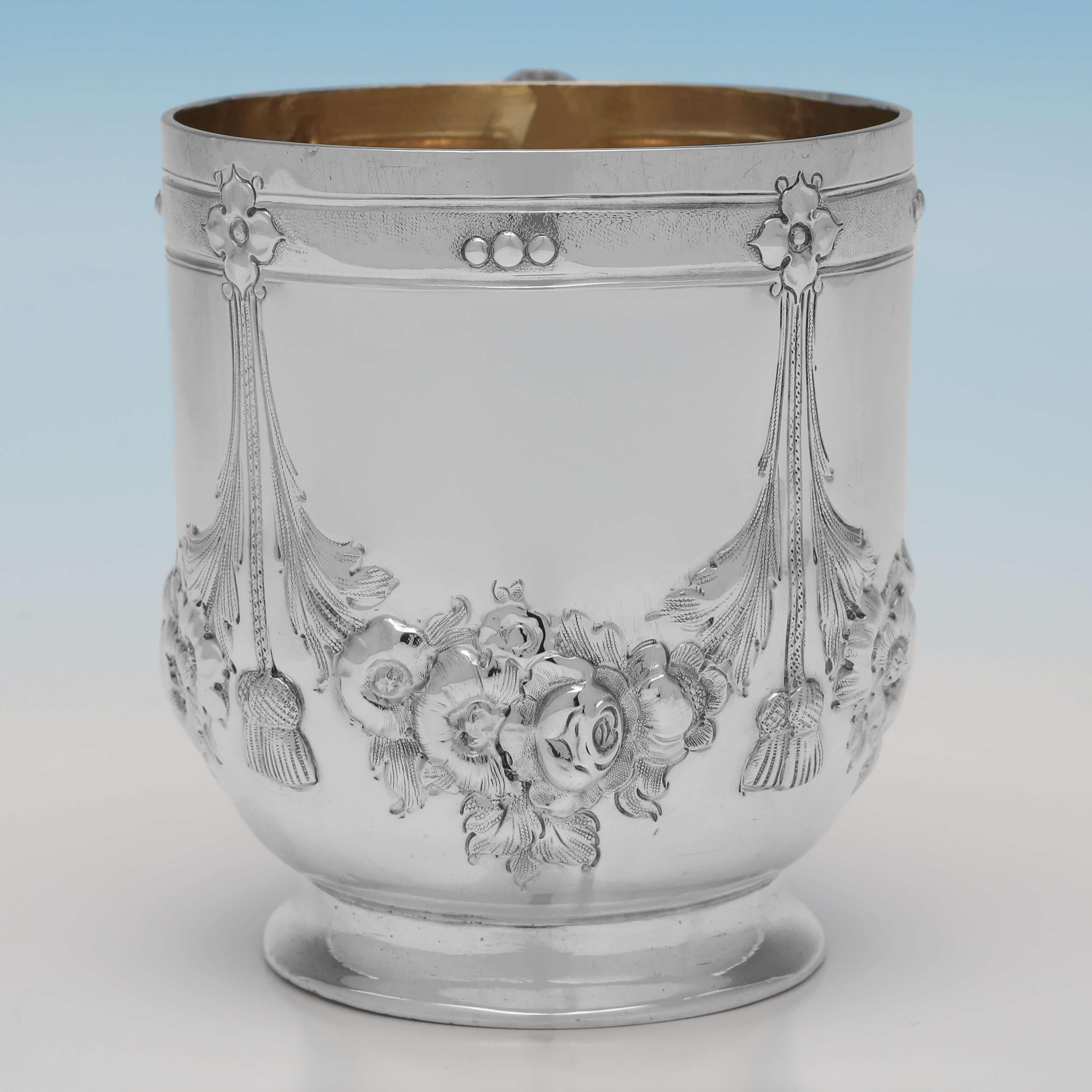 Hallmarked in London in 1867 by Henry John Lias & Son, this attractive, Victorian, Antique Sterling Silver Christening Mug, features chased and engraved decoration to the body, and a gilt interior. 

The christening mug measures 3.25