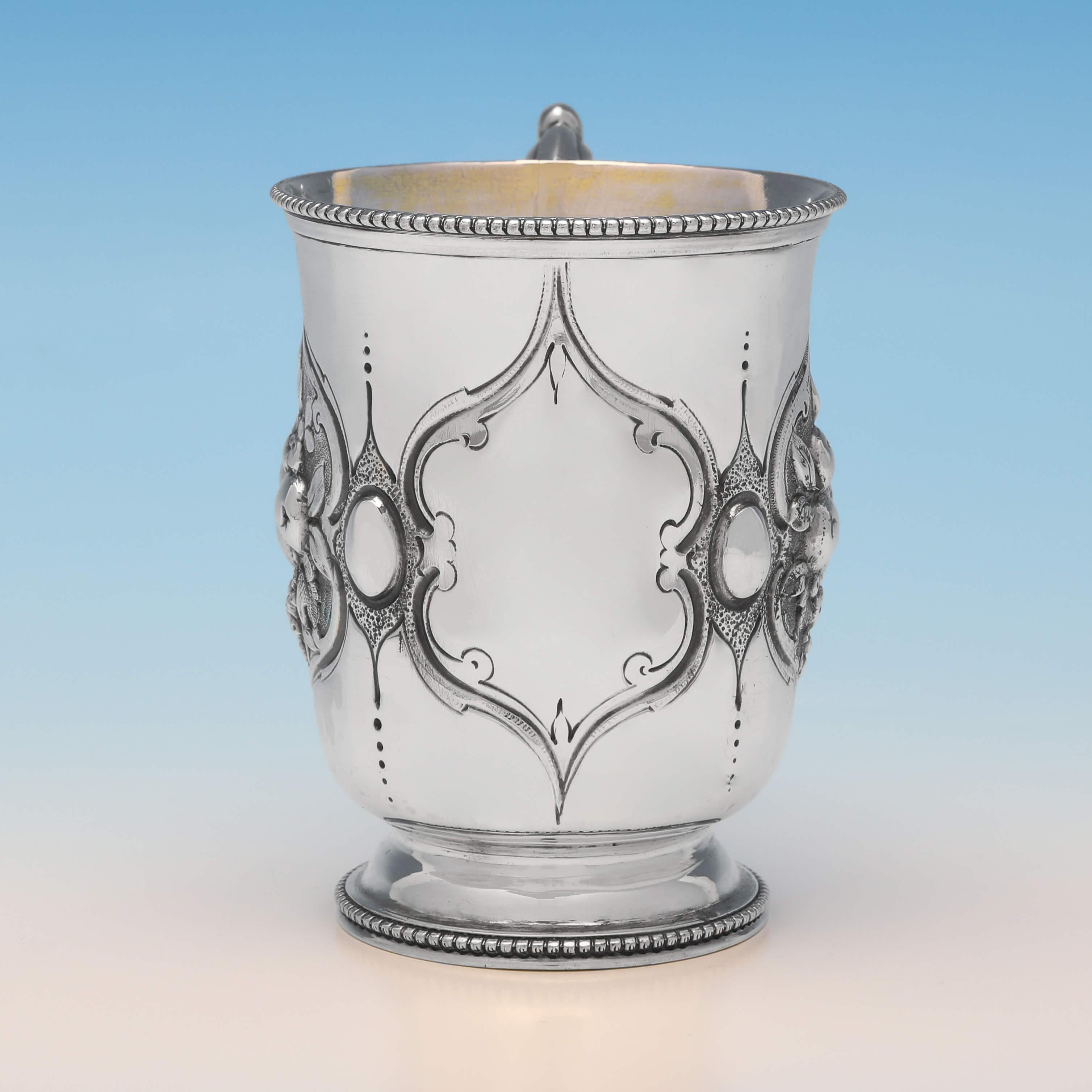 Hallmarked in London in 1866 by Henry Holland, this very attractive, Victorian, antique sterling silver christening mug, features chased and engraved decoration to the sides, a gilt interior and bead borders. The christening mug measures