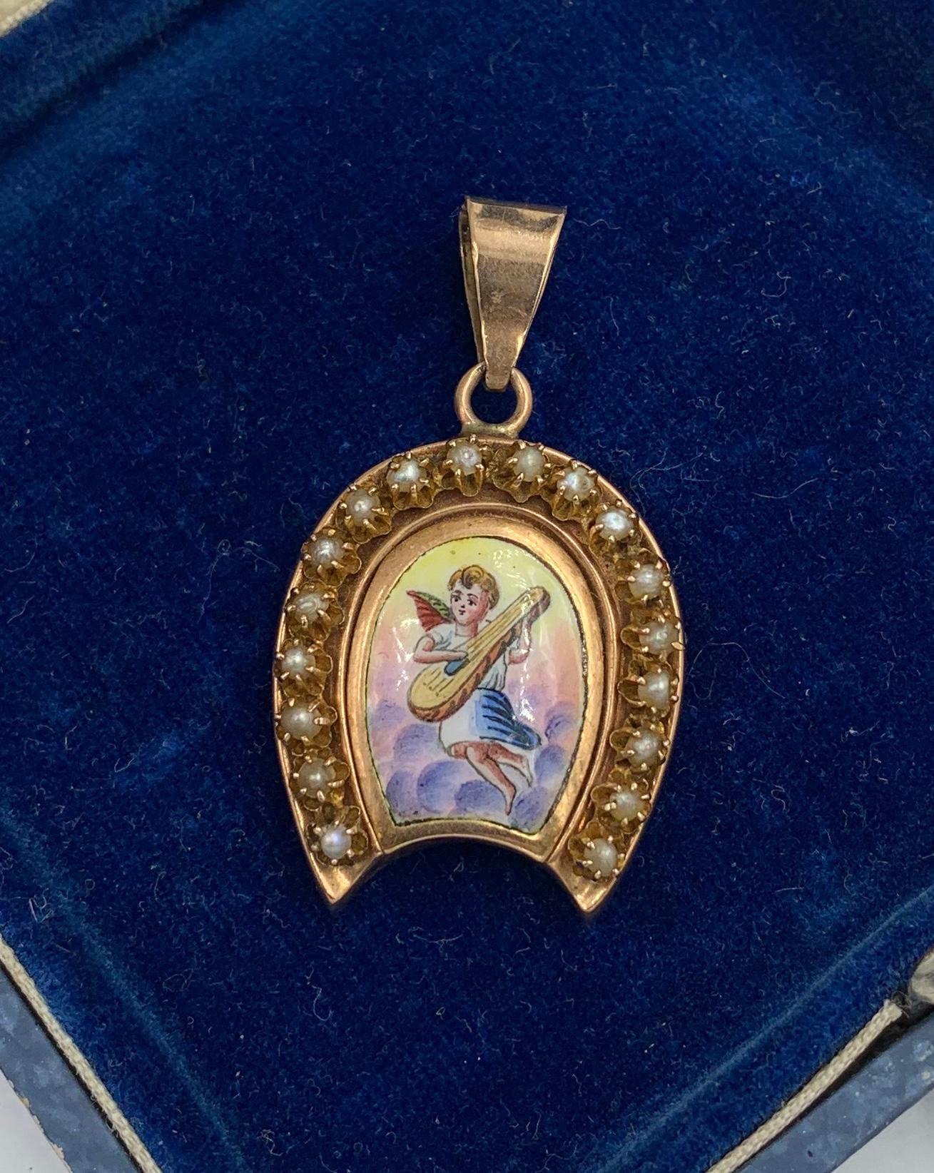A rare and wonderful Victorian locket pendant with an image of a Winged Cherub or Angel in the sky with clouds below and playing a lute or lyre.  The romantic and charming image is done in enamel with gorgeous colors and details.  The Horseshoe