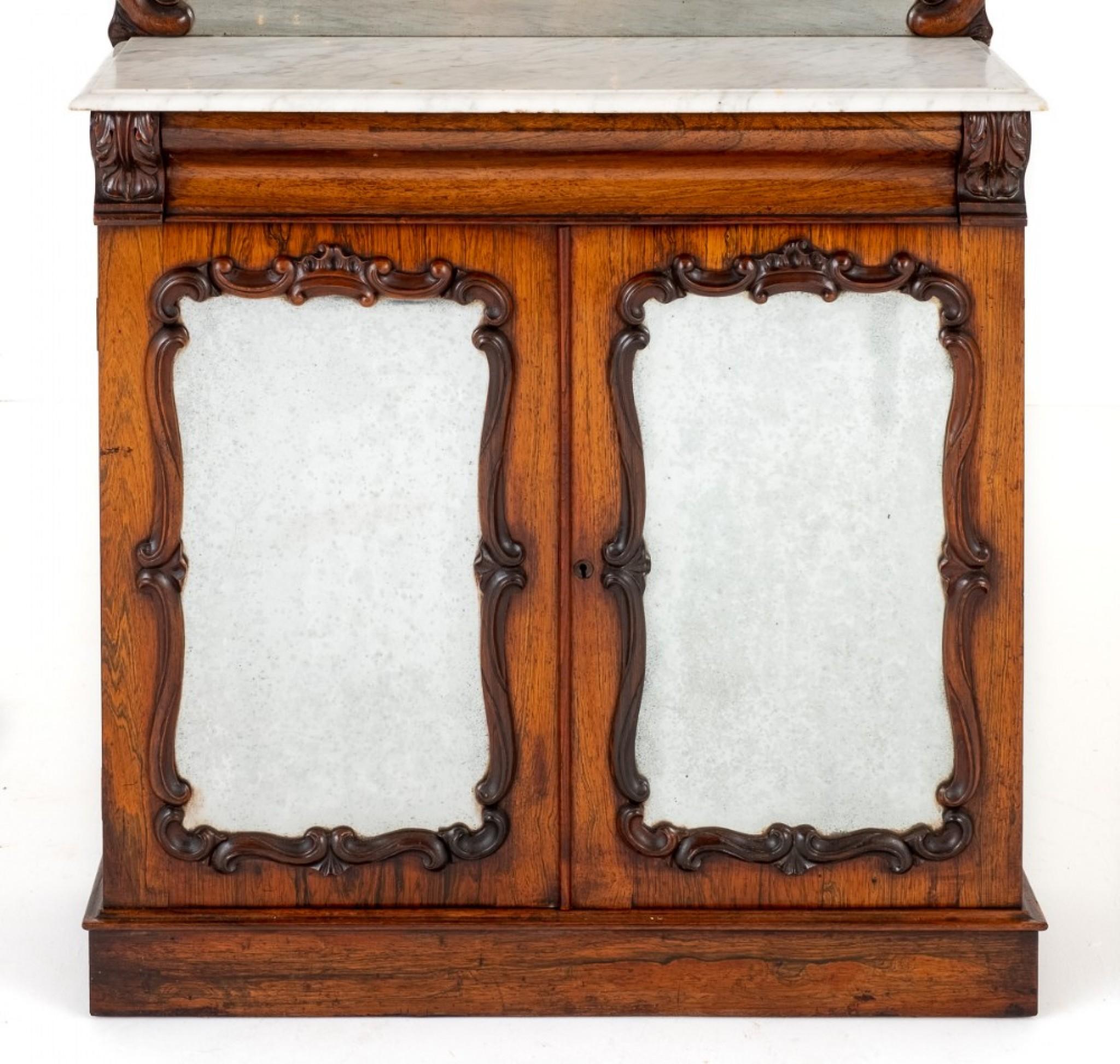 Rosewood marble Top Chiffonier.
Standing Upon a Plinth Base.
Circa 1860
The Lower Doors Being of a Mirrored Form with Carved Decorations.
The Doors Open to Reveal 1 Interior Shelf.
Above the Doors there is a Mahogany Lined Shaped Drawer.
The