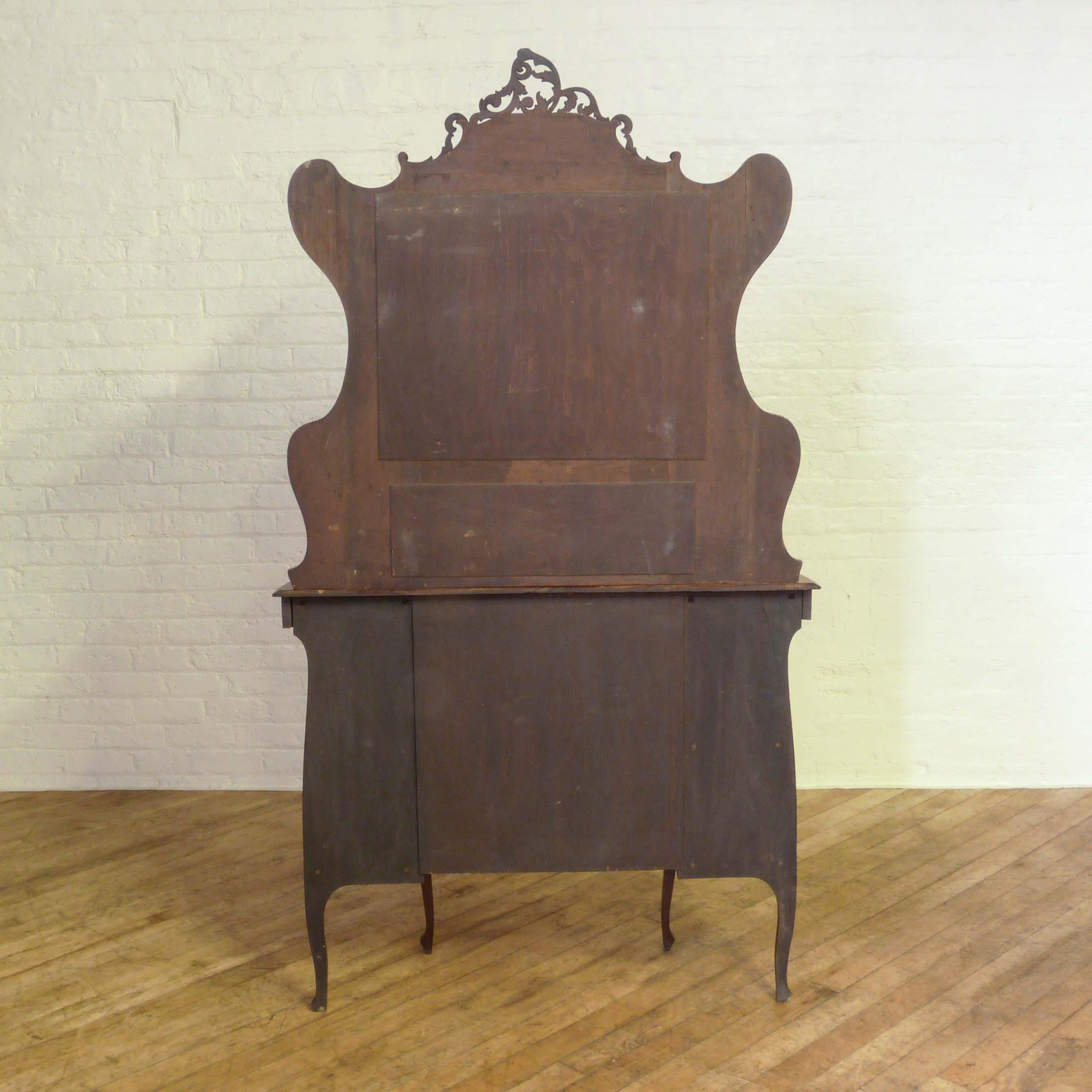 A Victorian walnut chiffonier side cabinet with a strong Rococo influence to its design. Other than old blemishes to the bevelled mirrors this piece is in superb condition. As some prefer to retain the mirrors as original we have not re-silvered