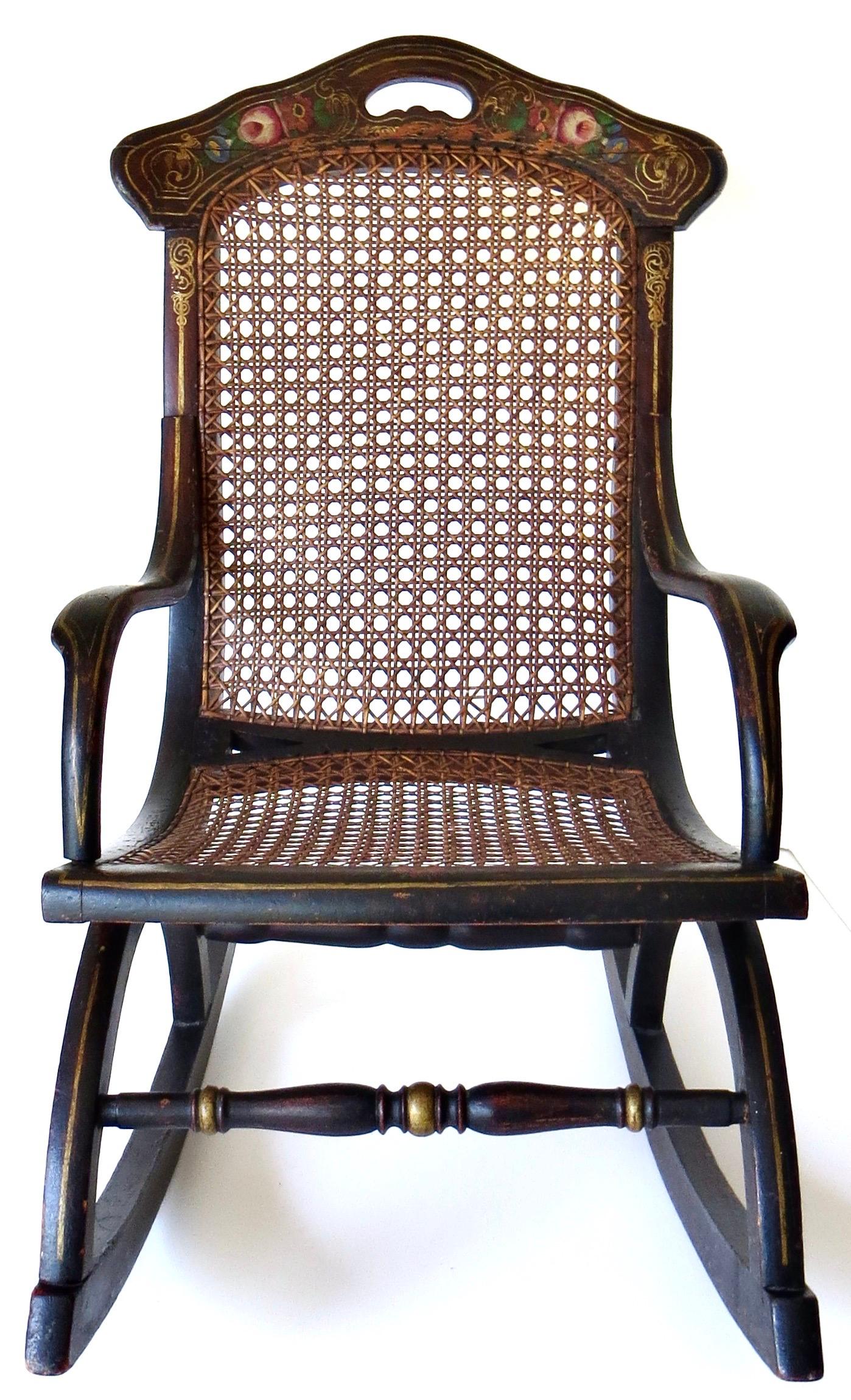 Charmante chaise à bascule d'enfant en bois dur datant du milieu de l'époque victorienne, ébonisée avec un pochoir floral polychrome peint à la main sur la traverse supérieure du dossier en bleu, vert et rouge ; pochoir de lignes dorées et de fleurs