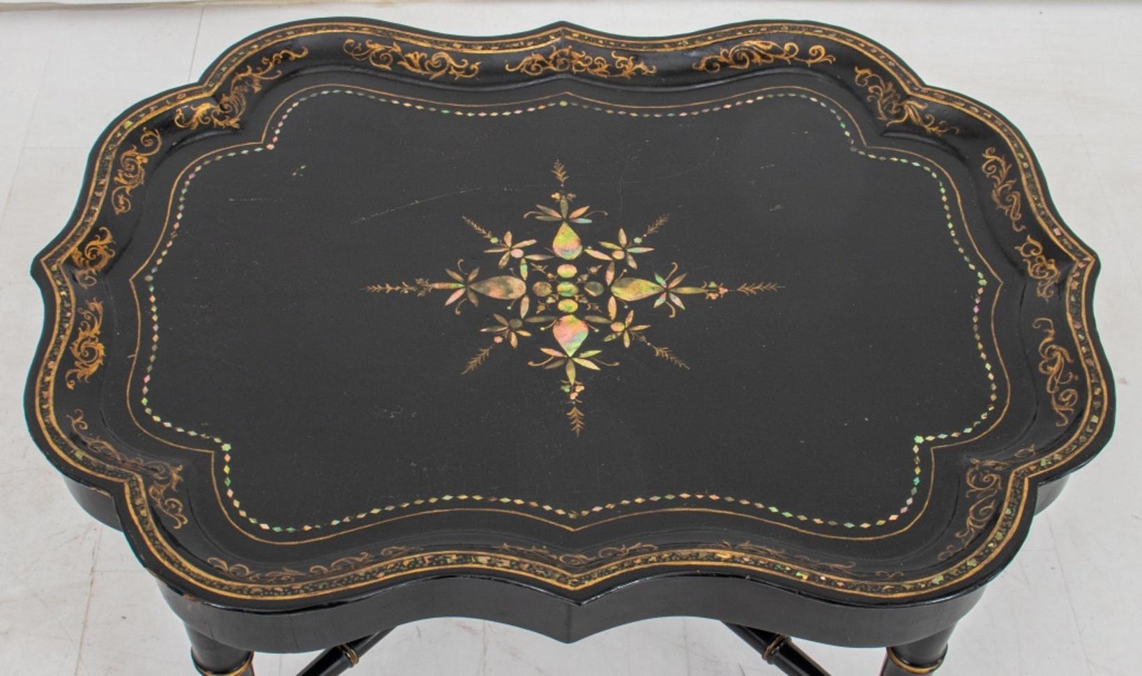 Victorian chinoiserie lacquered and abalone inlaid (papier-mache) tray table, with scalloped edges inlaid with shell fragments, the tray lacquered black with gilt decoration to surface and rim, the tray resting upon a conforming bamboo style base