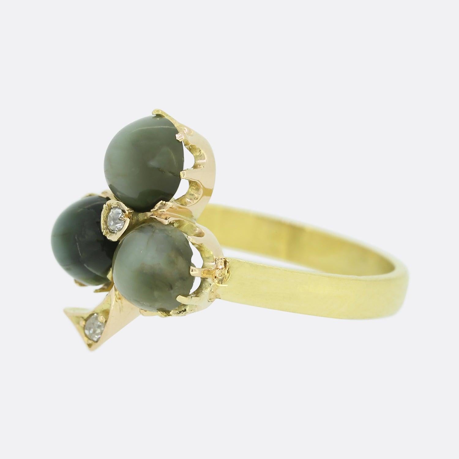 This is a charming Victorian diamond and chrysoberyl cats eye clover ring. The ring is set with a trio of round cabochon cats eye chrysoberyl with a central old cut diamond. The ring has been crafted in 18ct yellow gold with a plain polished band.