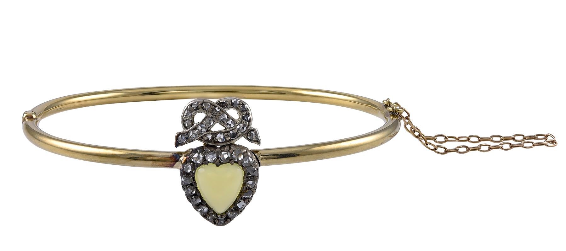 The Chrysoprase Heart of a luminous vaseline green colour, with a Rose Diamond set Silver on Gold 
surround and with a Rose Diamond Lovers Knot above.The slender tubular bangle, testing for 15k Gold, with a good clasp and safety chain and all in