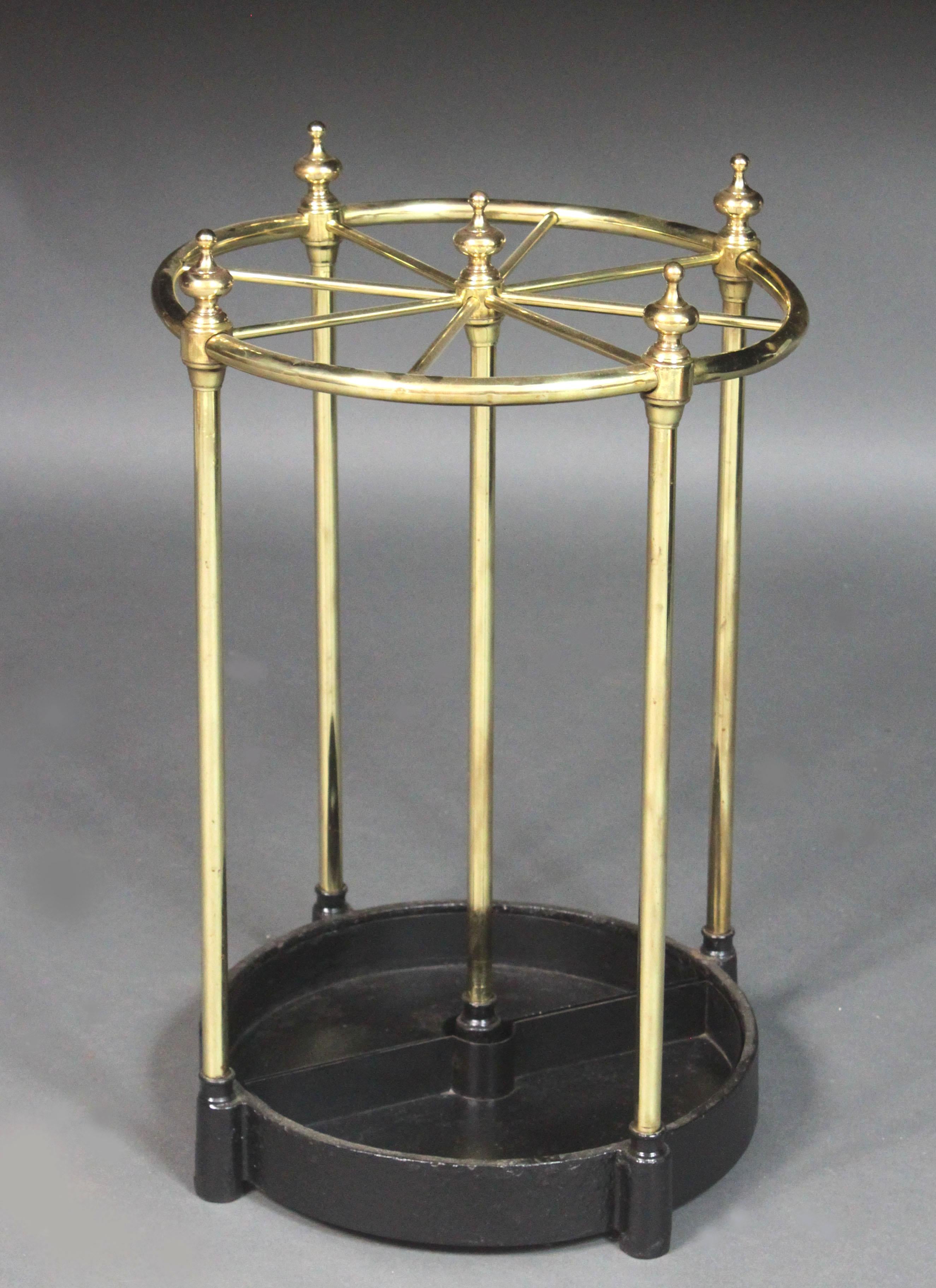 A good Victorian circular brass stick stand: made from brass rod with cast finials, cast iron base with removable drip trays