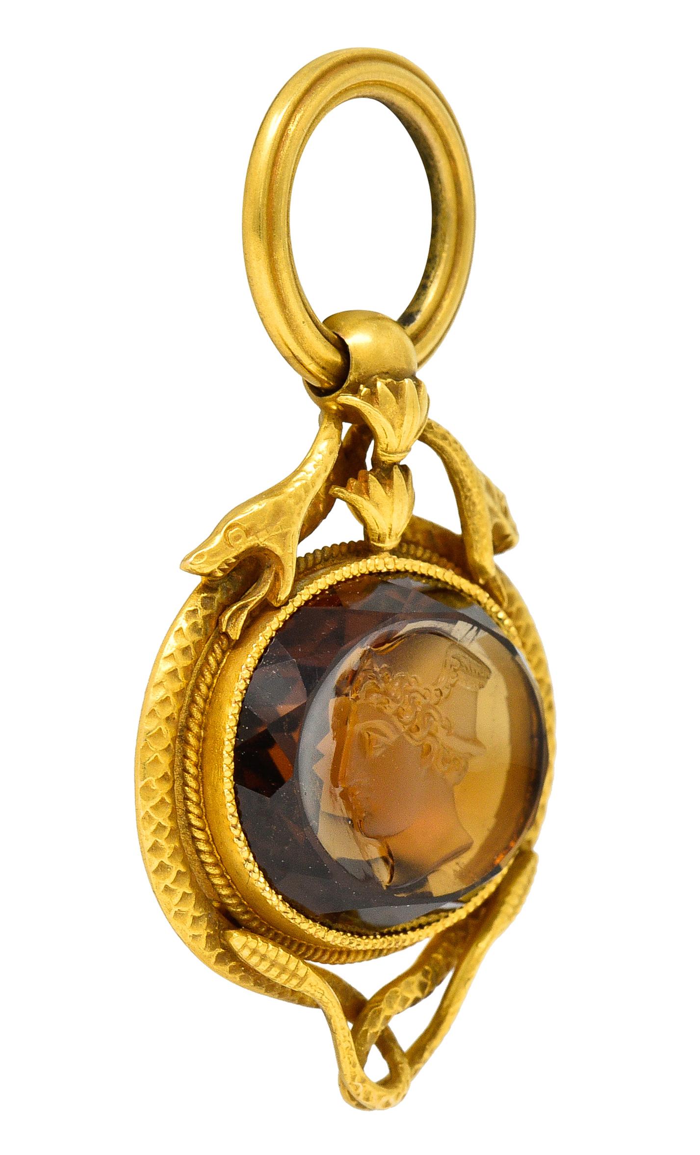 Centering a mixed cut oval citrine intaglio measuring 15.0 x 19.0 mm - transparent medium orangey brown. Carved to depict the Greek god Hermès wearing his signature winged helmet. Set in milgrain bezel with dual snake surround - known as caduceus,