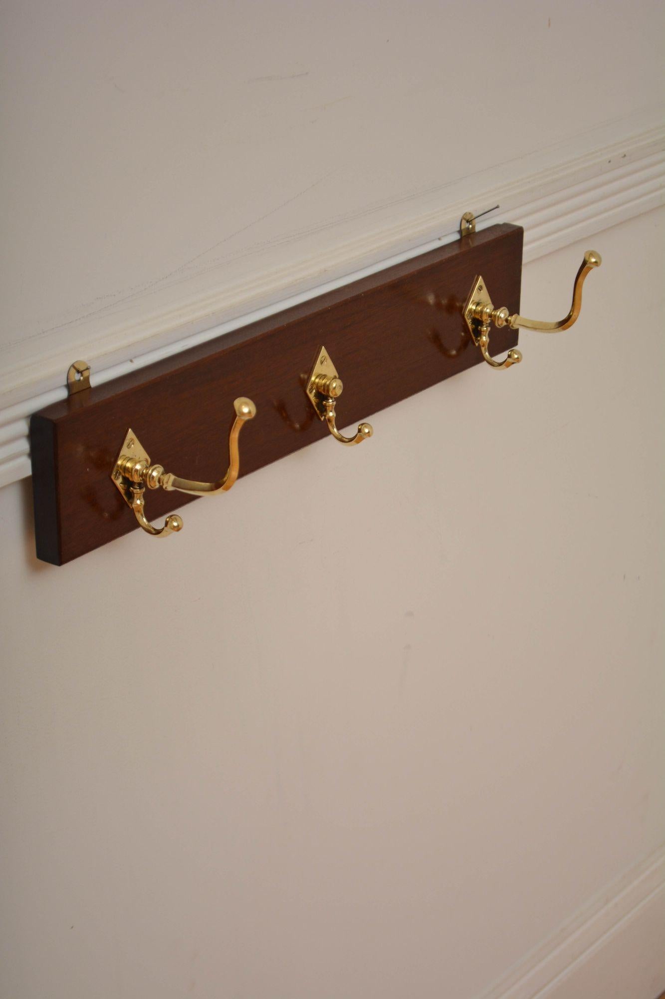 K0308 Attractive set of three brass coat and hat hooks on solid mahogany backing. Cleaned, polished and fitted with wall fittings this antique coat rack is in home ready condition. c1880
H4.5