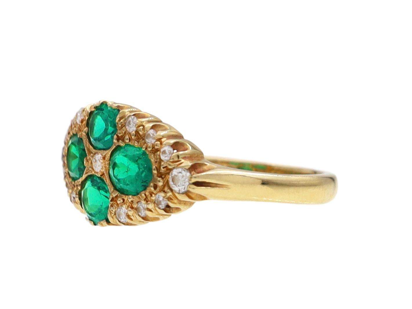 Victorian Colombian emerald and diamond horizontal marquise cluster ring in 18kt yellow gold. Set with four oval mixed cut Colombian emeralds in grain settings, further highlighted to the centre and throughout with round eight cut diamonds in grain