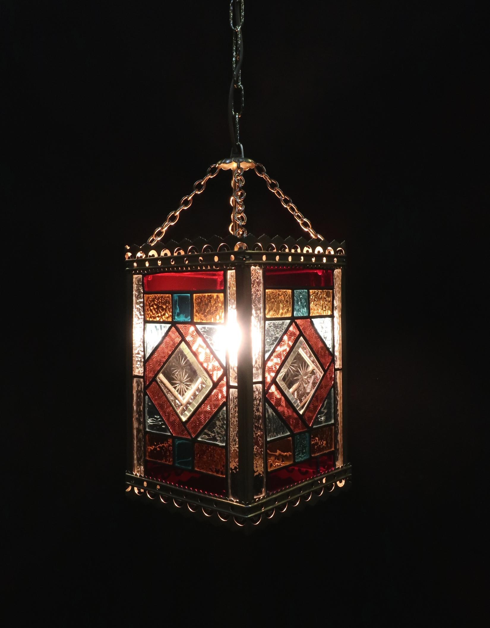 A very decorative Victorian hall lantern with brass frame retaining its original colored glass panels. The panels consist of red, blue, orange, yellow and clear rippled and textured glass with a bevelled glass diamond shaped centre with engraved