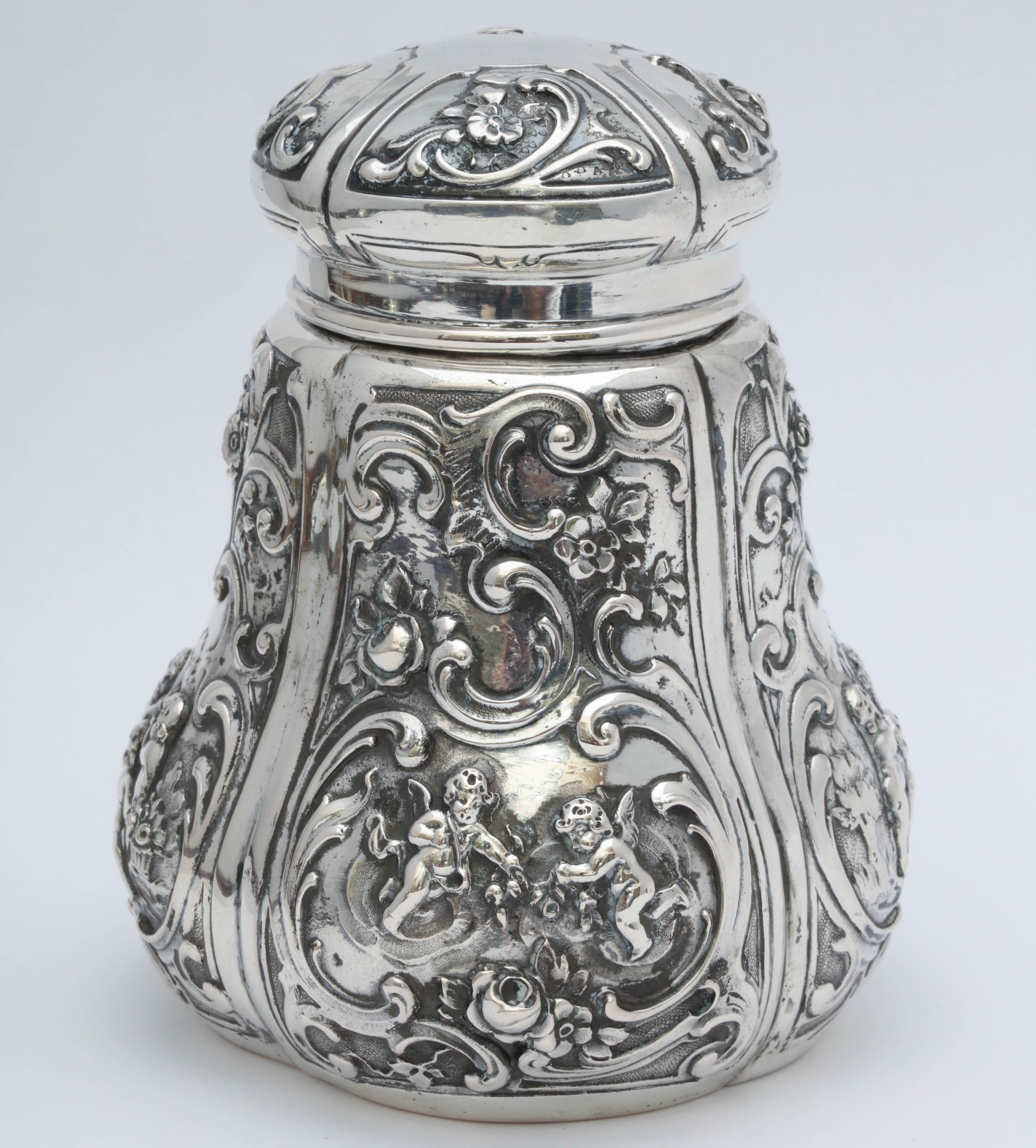 Victorian, Continental silver (.800) tea caddy, Germany, circa 1895. Stands 4 3/4 inches high x 3 1/2 inches in diameter at widest point. Decorated with cherubs and flowers. Weighs 6.510 troy ounces. Dark spots in photos are reflections. Excellent