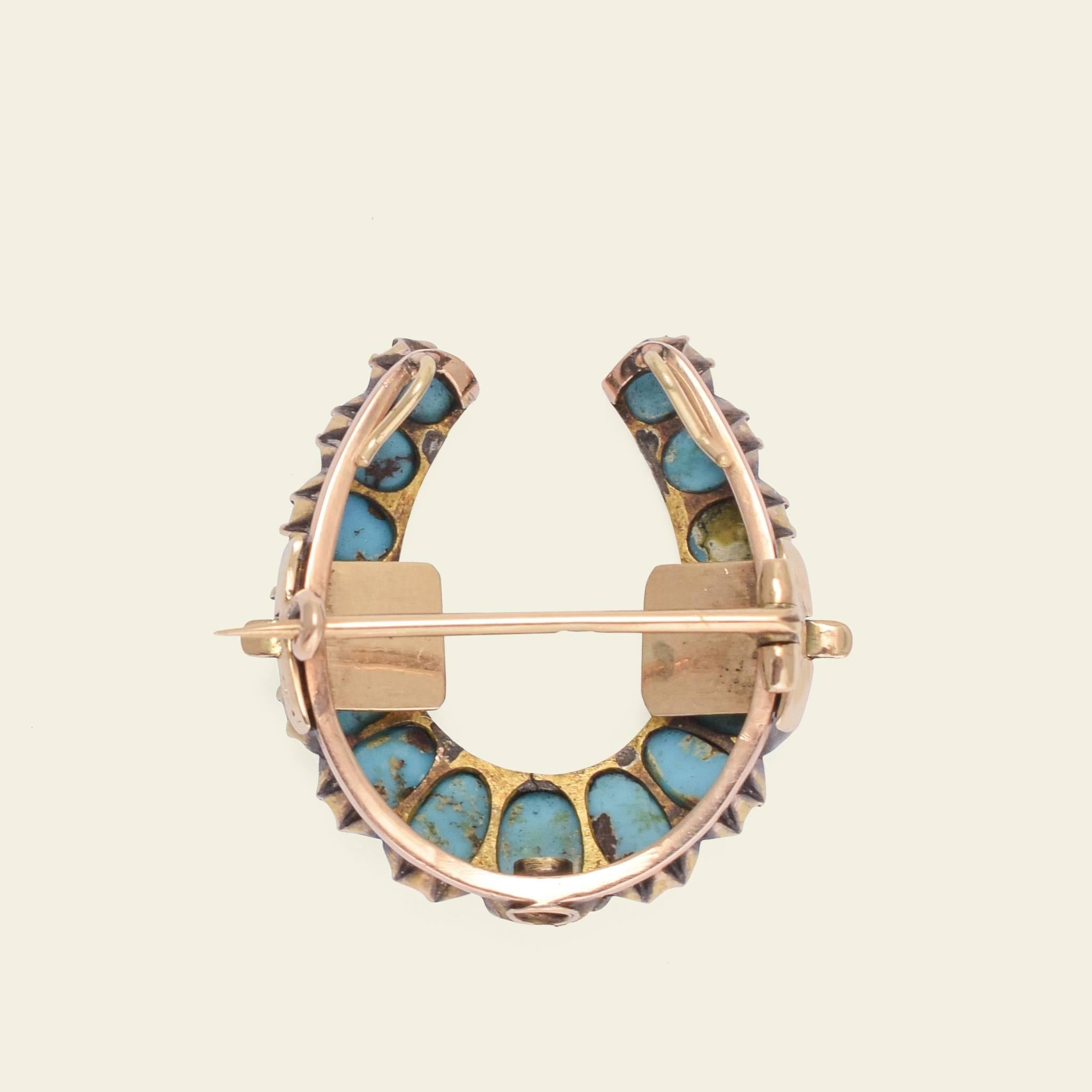 This ingenious piece of Victorian jewelry fashioned in the shape of a horseshoe is not just a brooch, but a brooch that seamlessly converts into a pendant. The lovely robin's egg blue turquoise cabochons that form the face of are mounted on a body