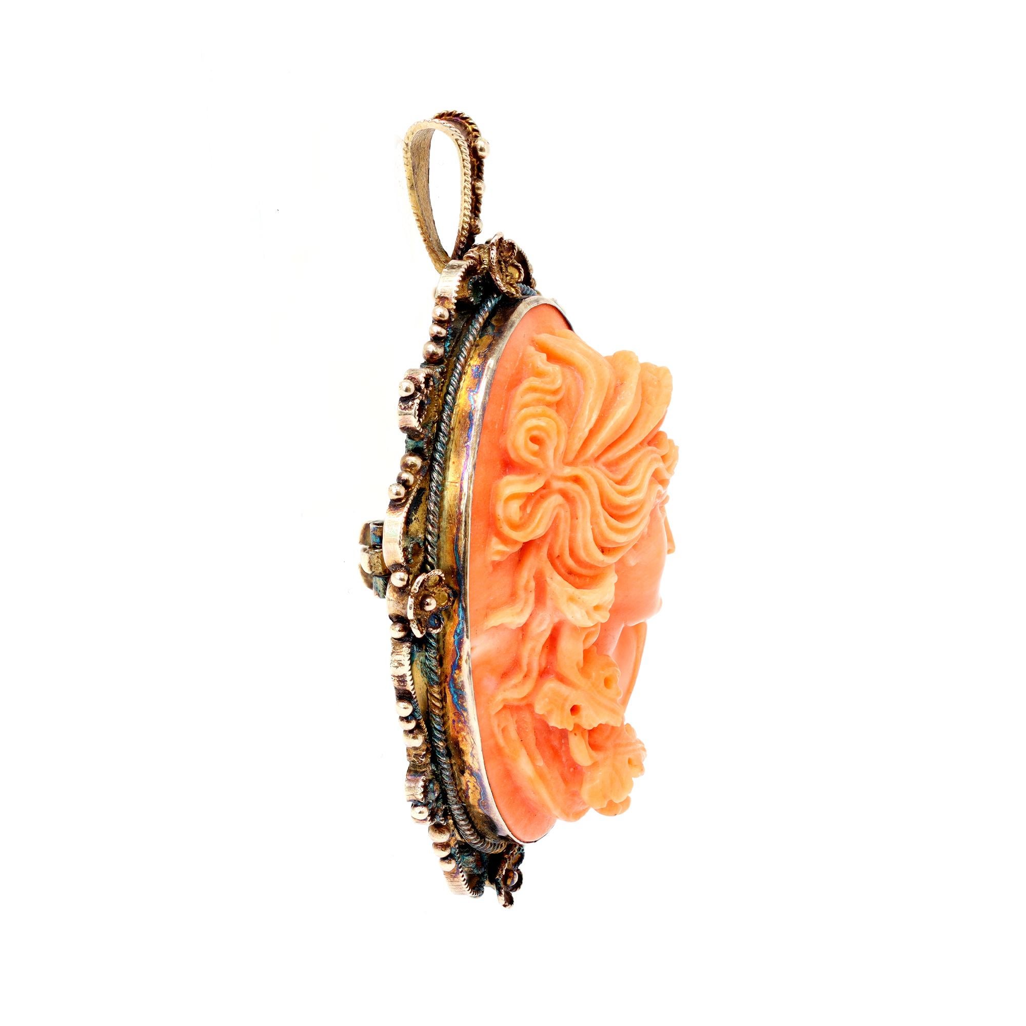 A striking and rare coral carving attributed to Italian craftsmanship, Circa 1900. The carving represents an intricate female figure with floral and leaf motifs around her neck. The coral is natural with no indication of dye. The bezel setting was