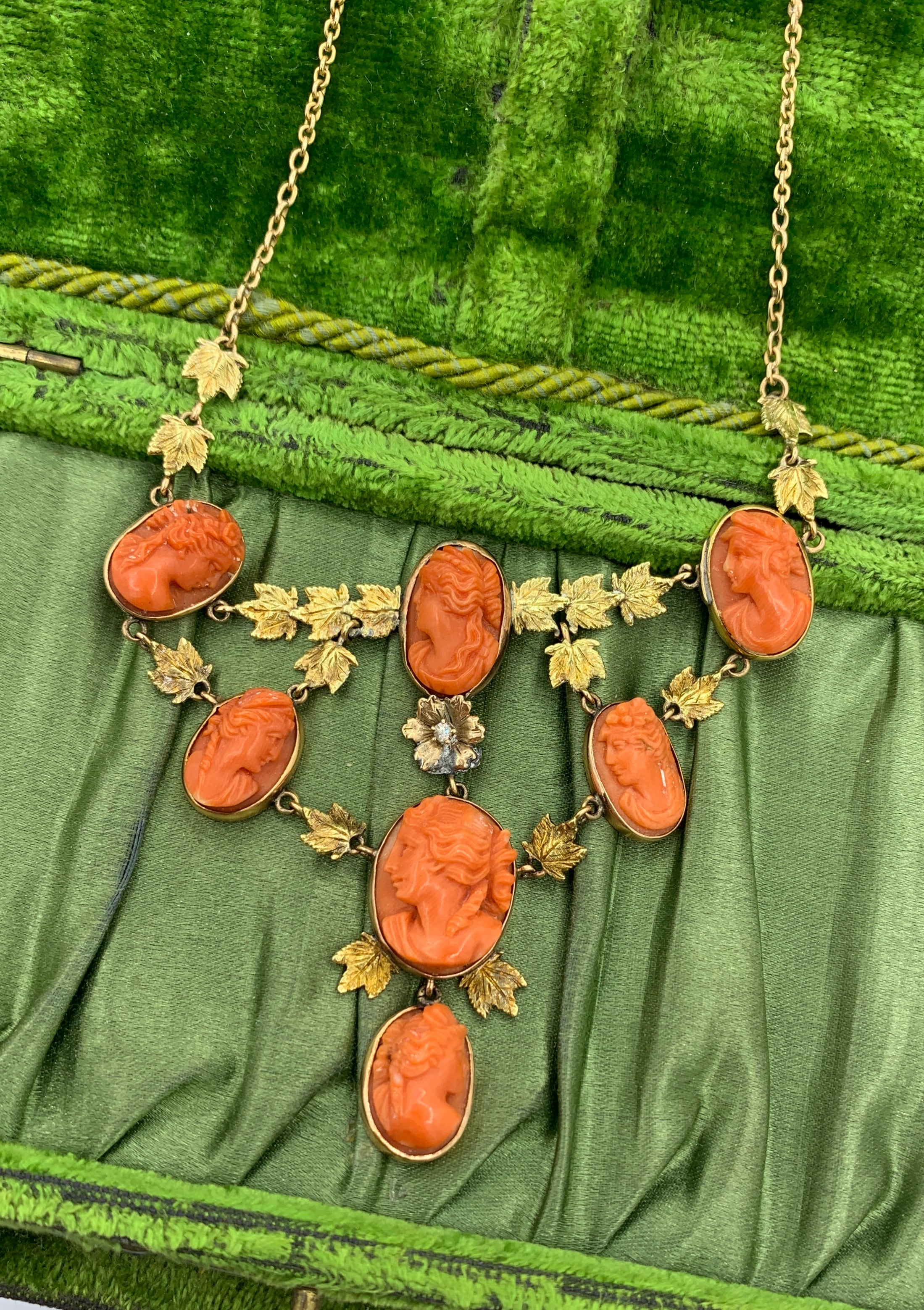 This is an absolutely stunning early antique Coral Cameo Pendant Necklace in 14 Karat Gold dating to the Victorian period with seven magnificent hand carved Coral Cameos in a leaf motif design with a central flower set with an Old Mine Cut Diamond.