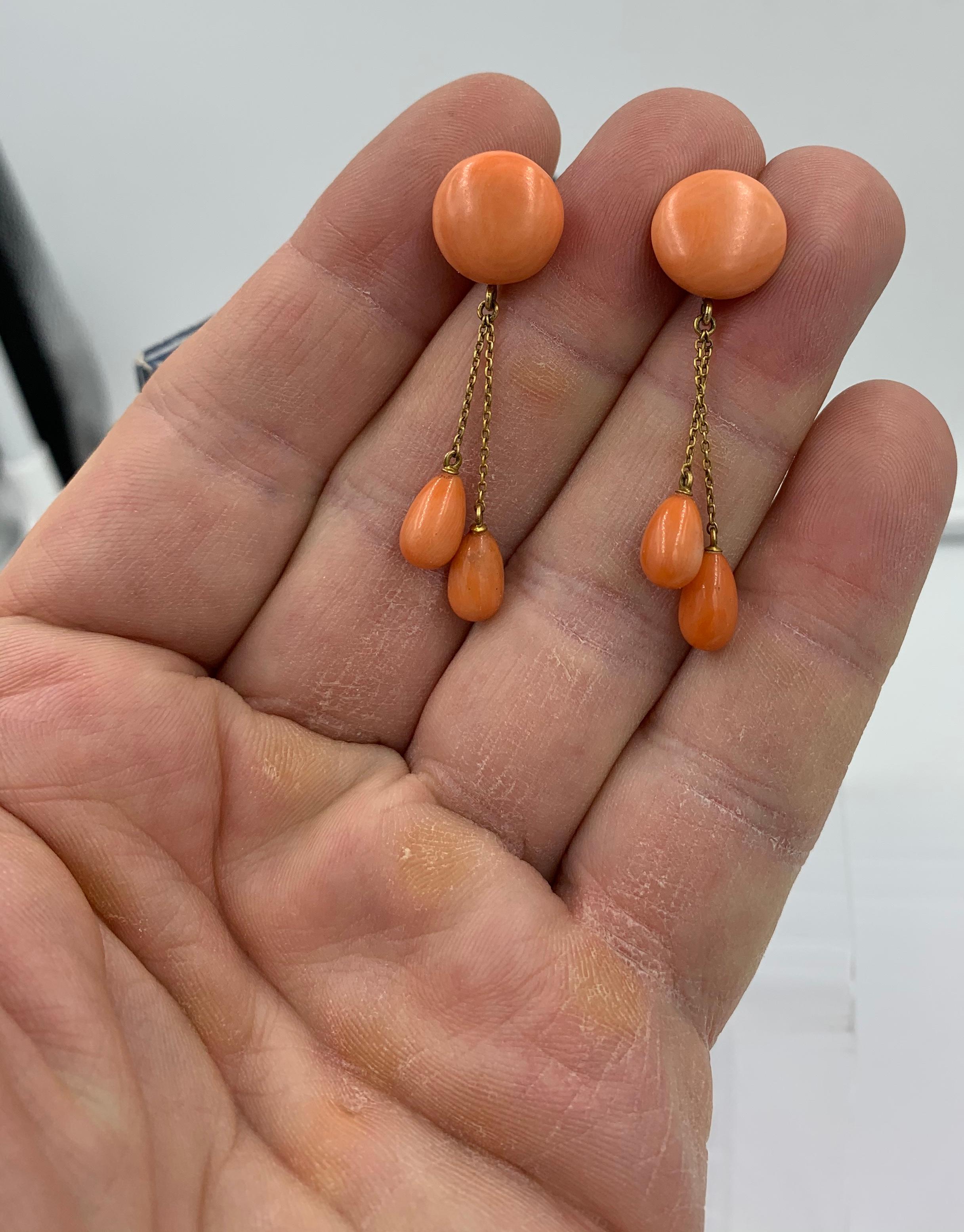 A gorgeous pair of Victorian Coral Dangle Drop Earrings in 14 Karat Gold.  The stunning 2 inch long earrings have round natural Coral cabochons of 14mm (just over 1/2 inch) in diameter at the top.  From the top hang two articulated chains with pear
