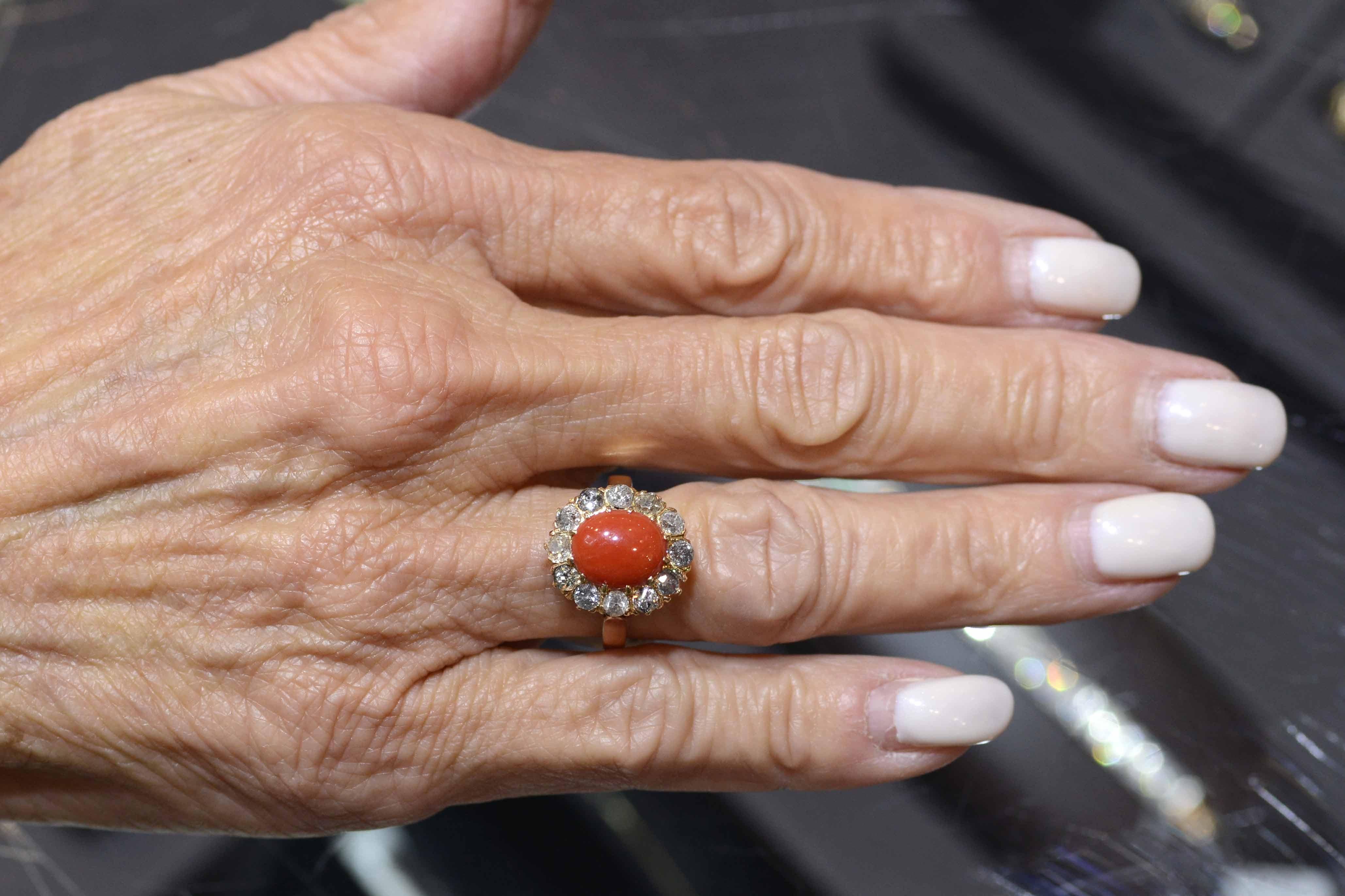 A delightful Victorian gemstone engagement ring centered by a most alluring, rich salmon coral cabochon oval. A 1 carat diamond halo of old mine cut diamonds (very rustic, salt and pepper gems) adds drama to this Circa 1890 antique heirloom